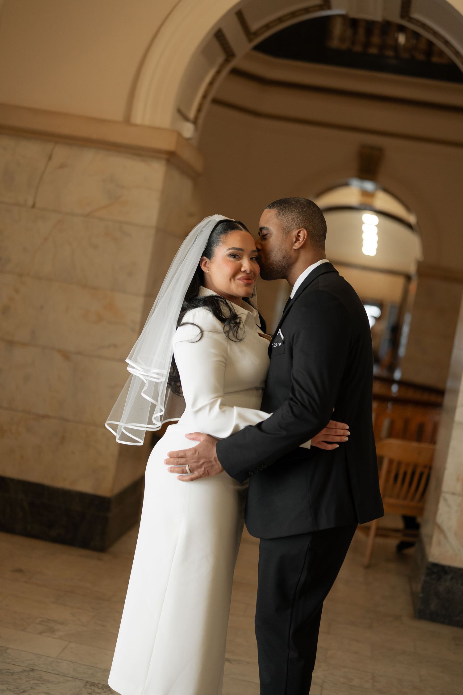 An intimate wedding portrait of a couple sharing a tender moment in a historic building.