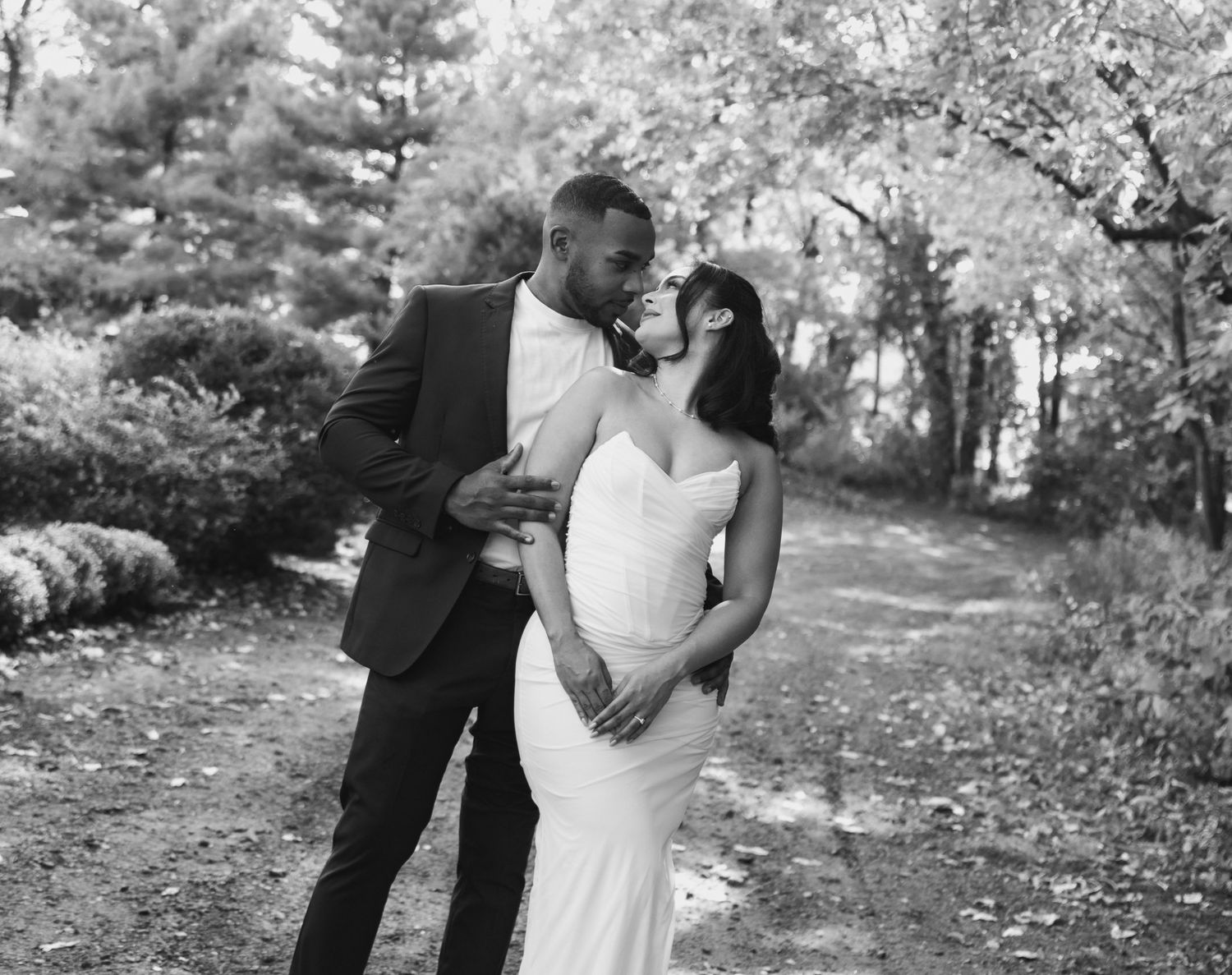 Black and white romantic wedding photo series showing intimate moments between newlyweds in a natural outdoor setting.