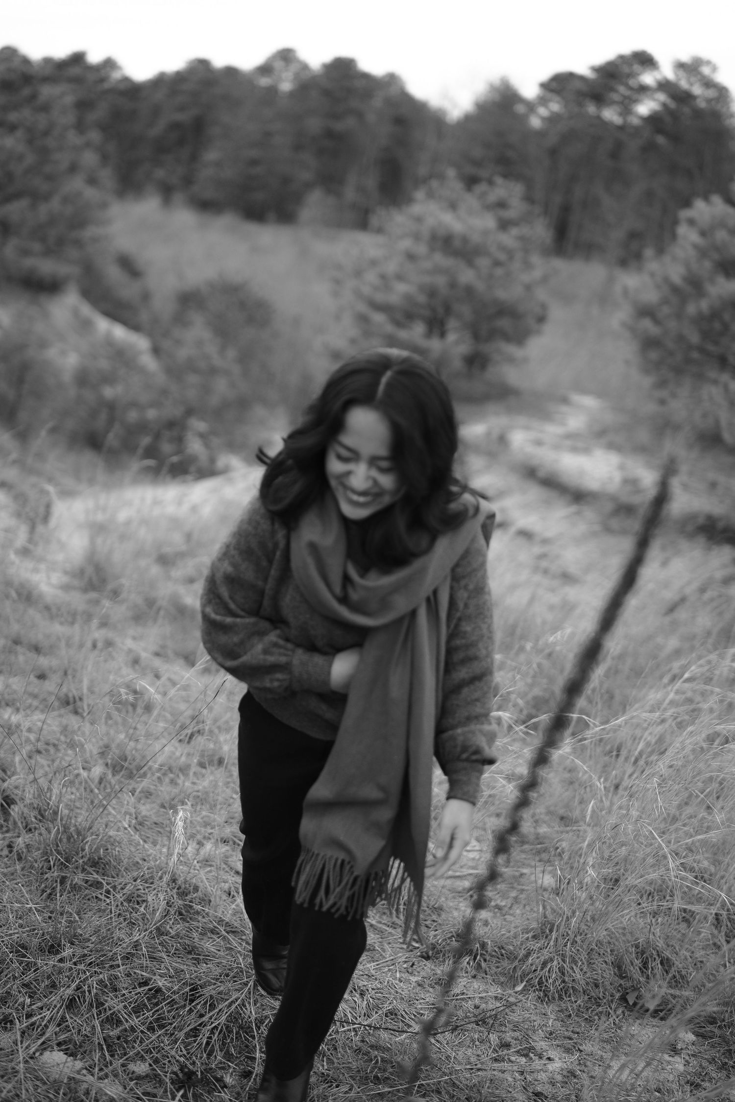 Black and white photos show someone in dark clothing laughing joyfully in a natural outdoor setting.