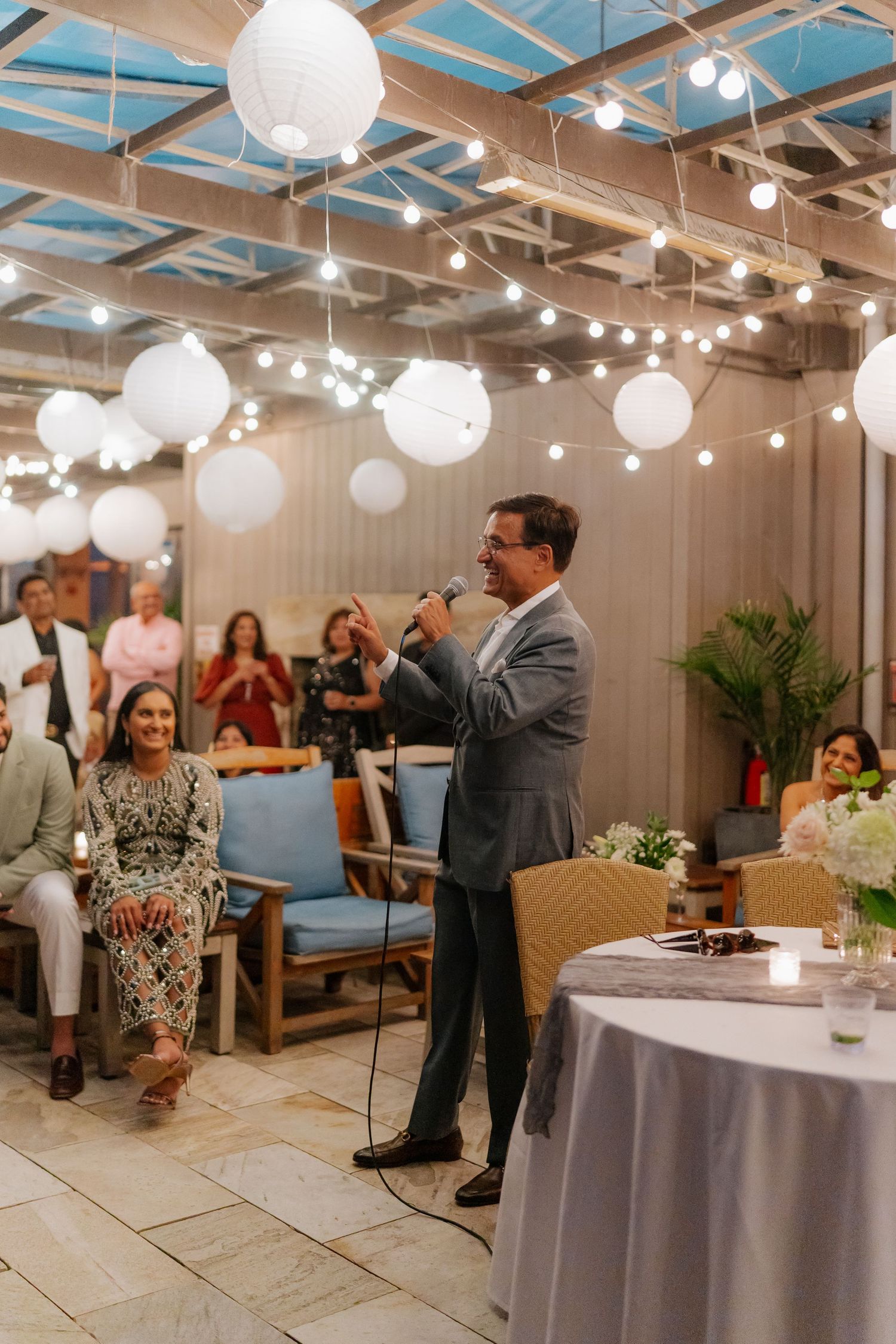 Indoor wedding reception venue decorated with paper lanterns and string lights.