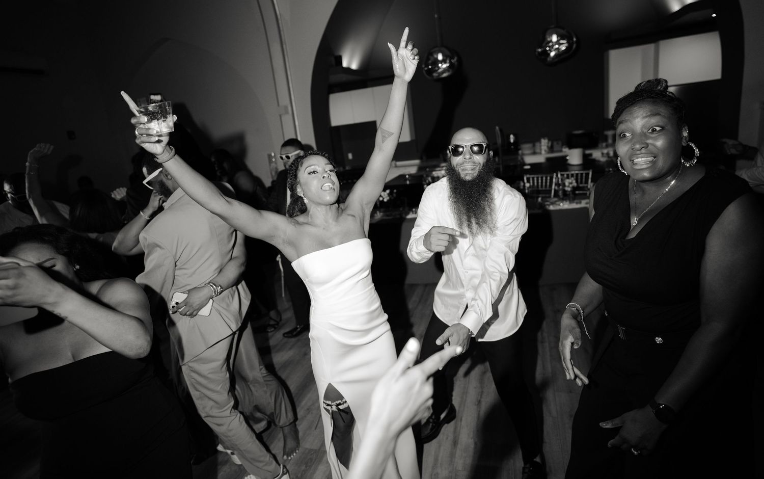 Wedding party dancing and celebrating with raised arms on the dance floor.