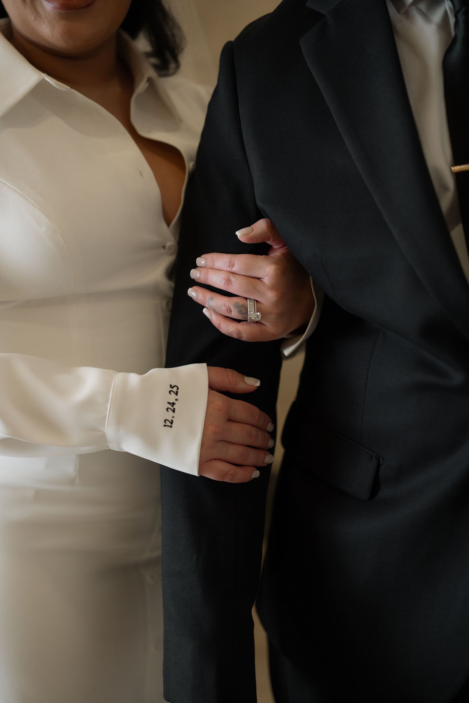 Close-up details of formal wedding attire and hands.