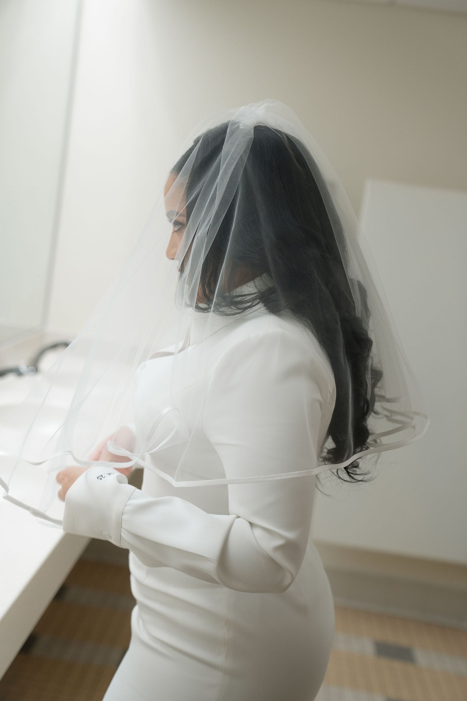 Person in white dress and black veil preparing for wedding ceremony.