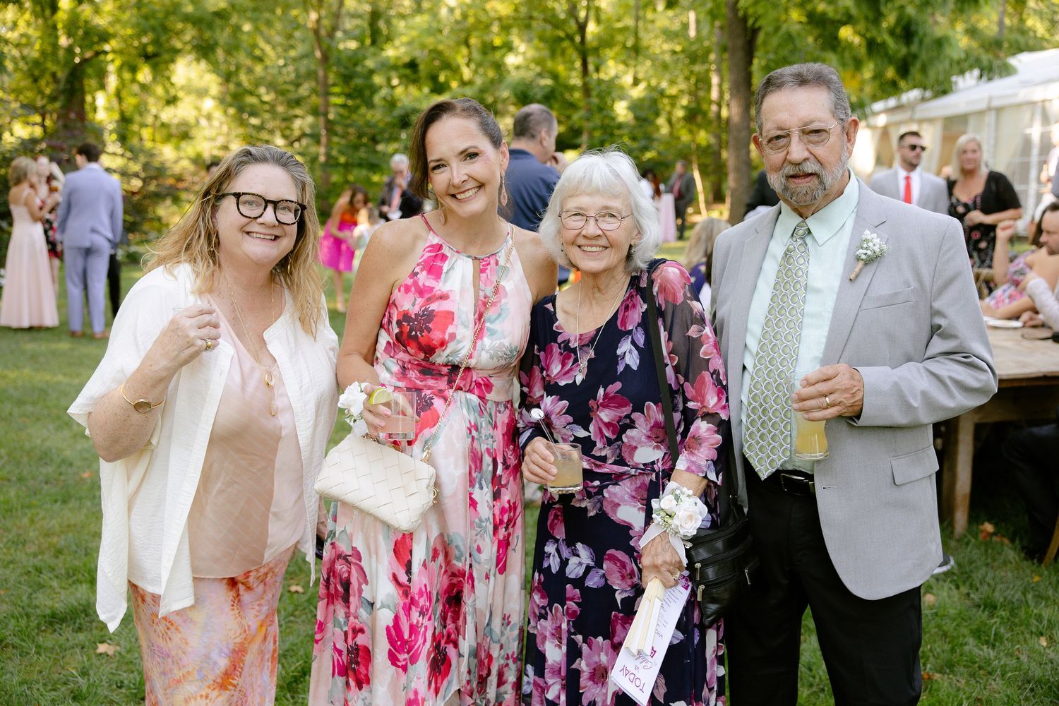Wedding guests mingling outdoors in pink and floral attire during a garden reception.