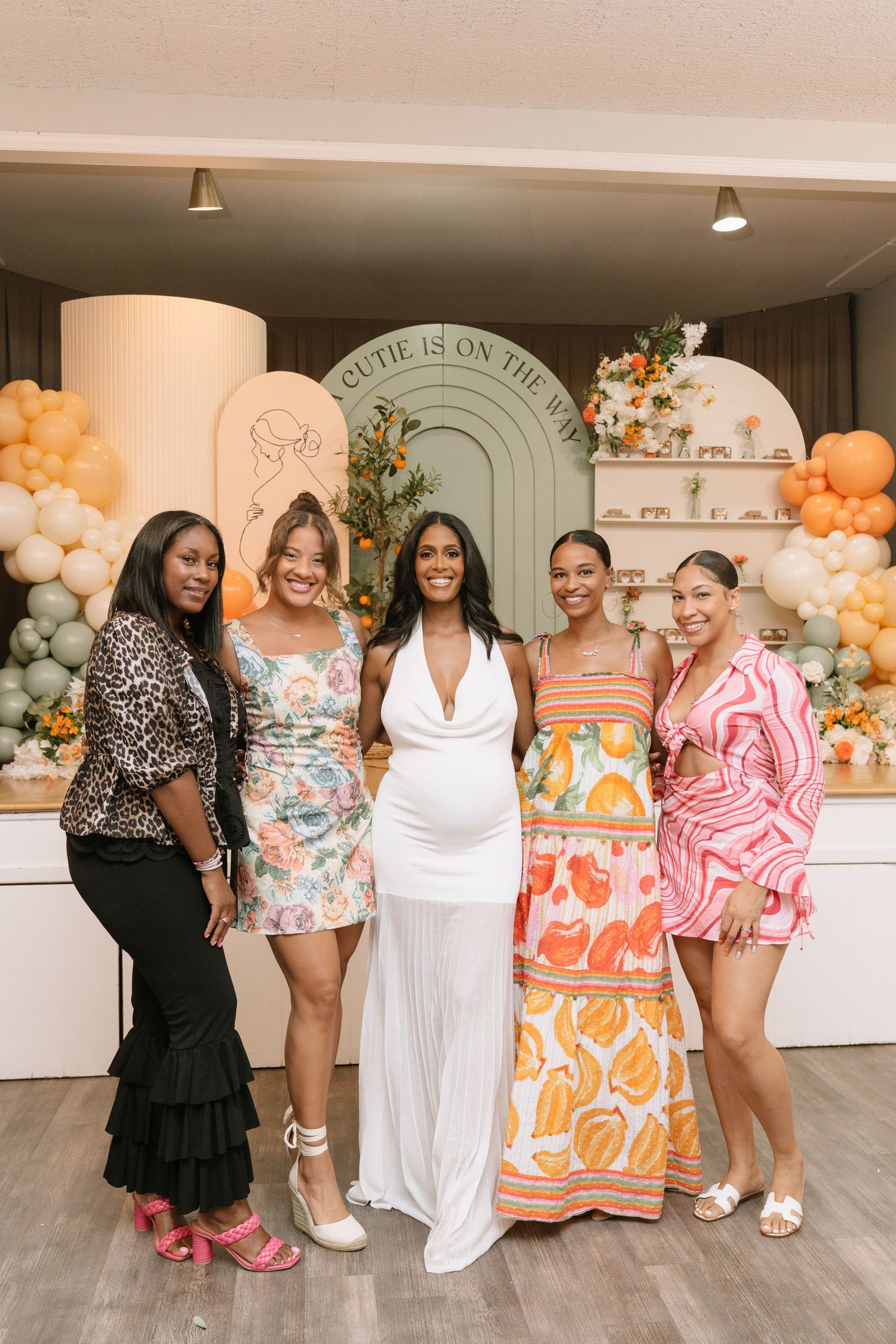 Group of women in colorful summer dresses posing at a celebration event.