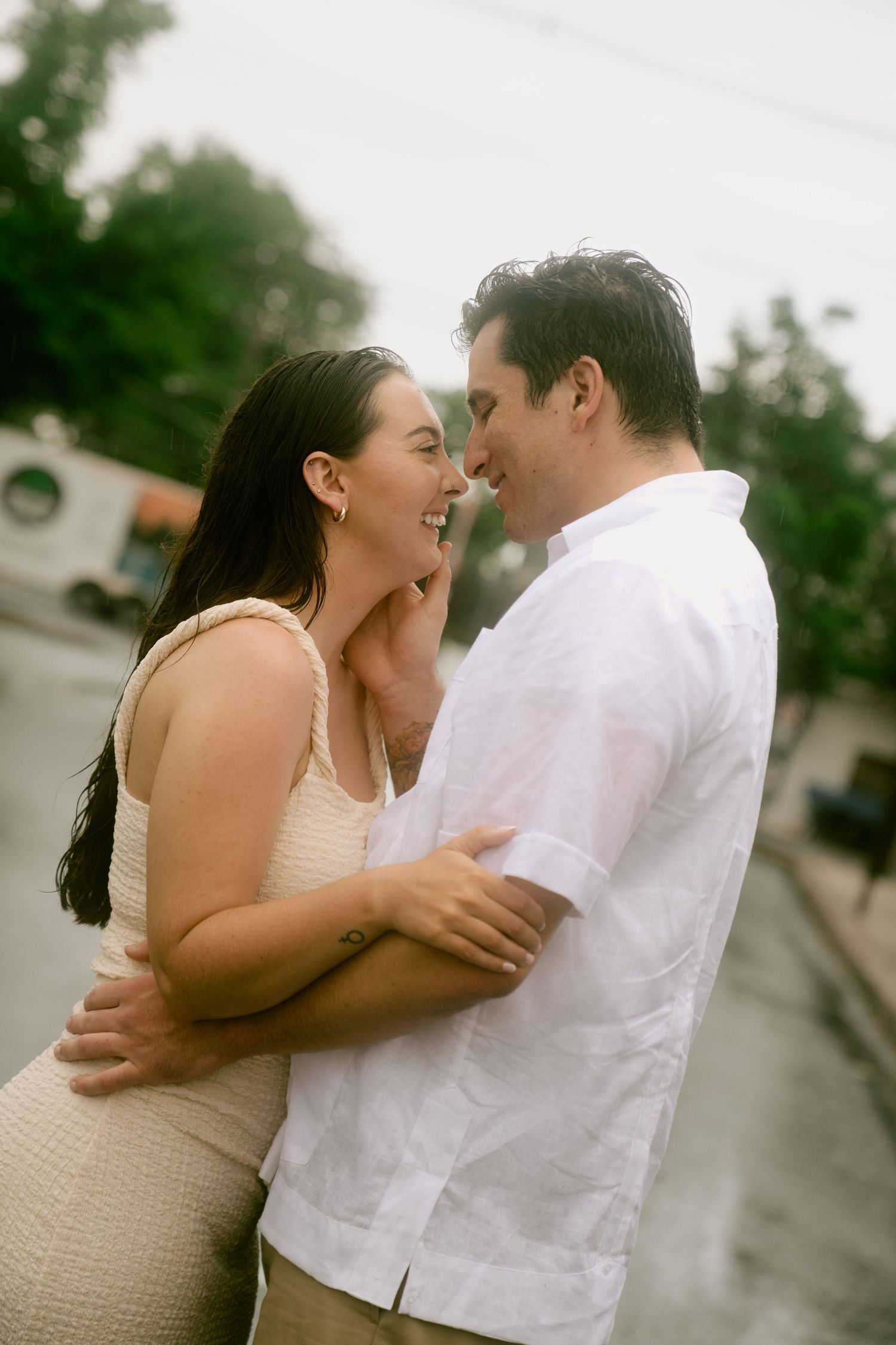 A couple in white attire share intimate romantic moments in a series of candid outdoor engagement photos.