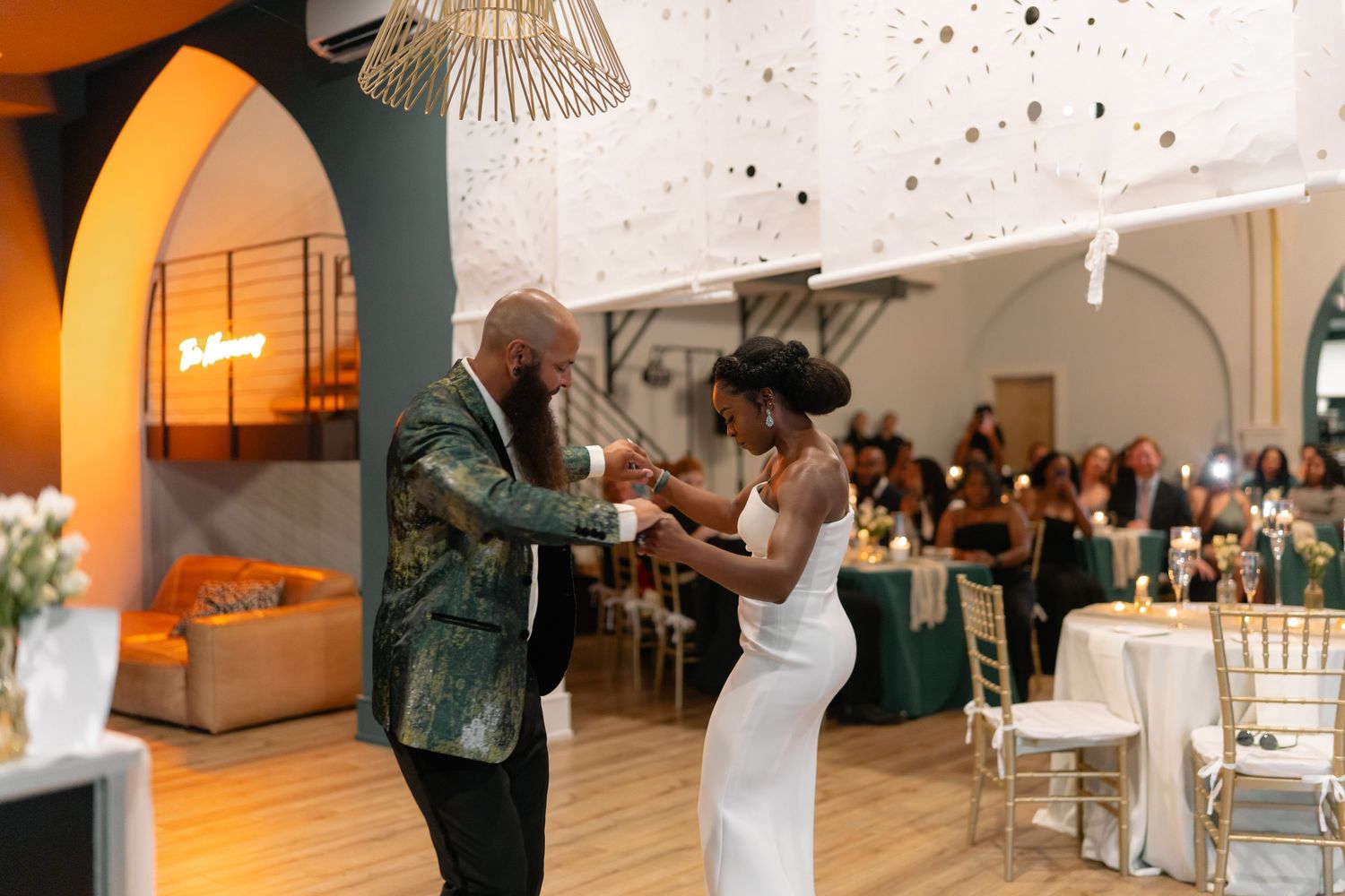 Wedding reception party with warm lighting and guests dancing in an elegant venue.