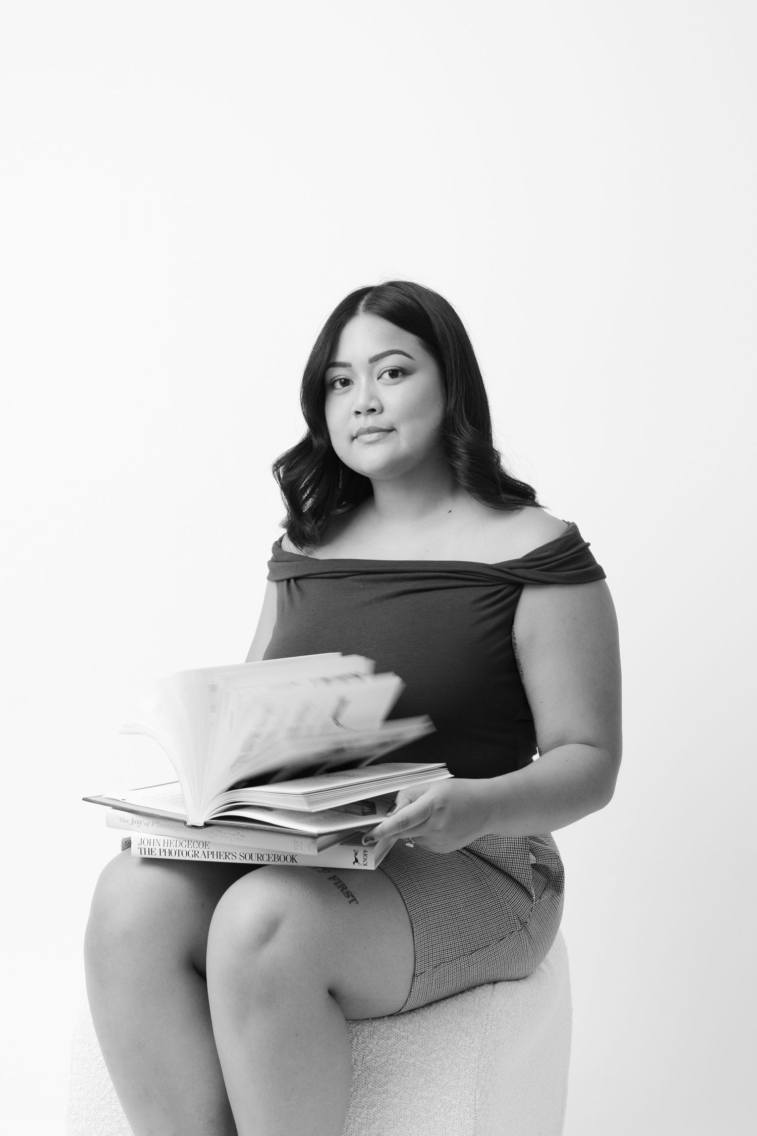 Artistic black and white portraits with books in minimalist studio setting.