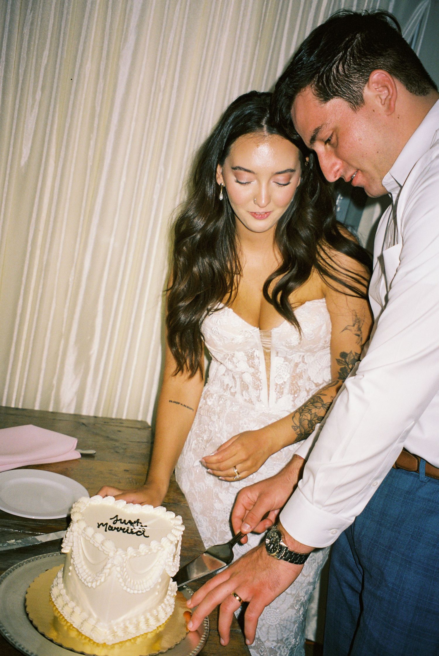 A couple cuts their small white wedding cake together at their reception.