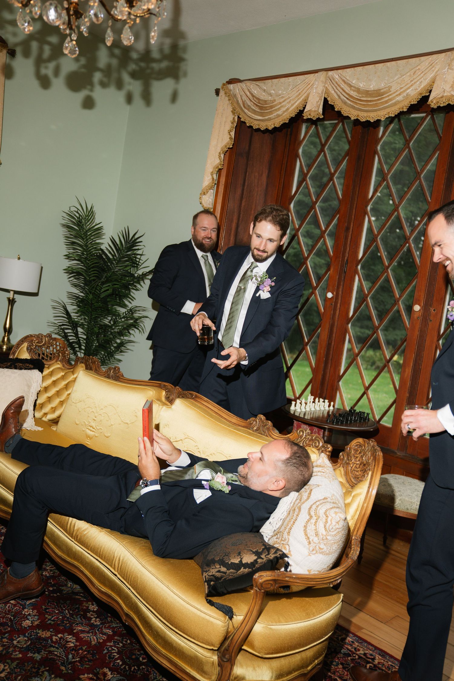 A sequence of photos showing people in suits playfully wrestling on a gold leather couch at a formal event.