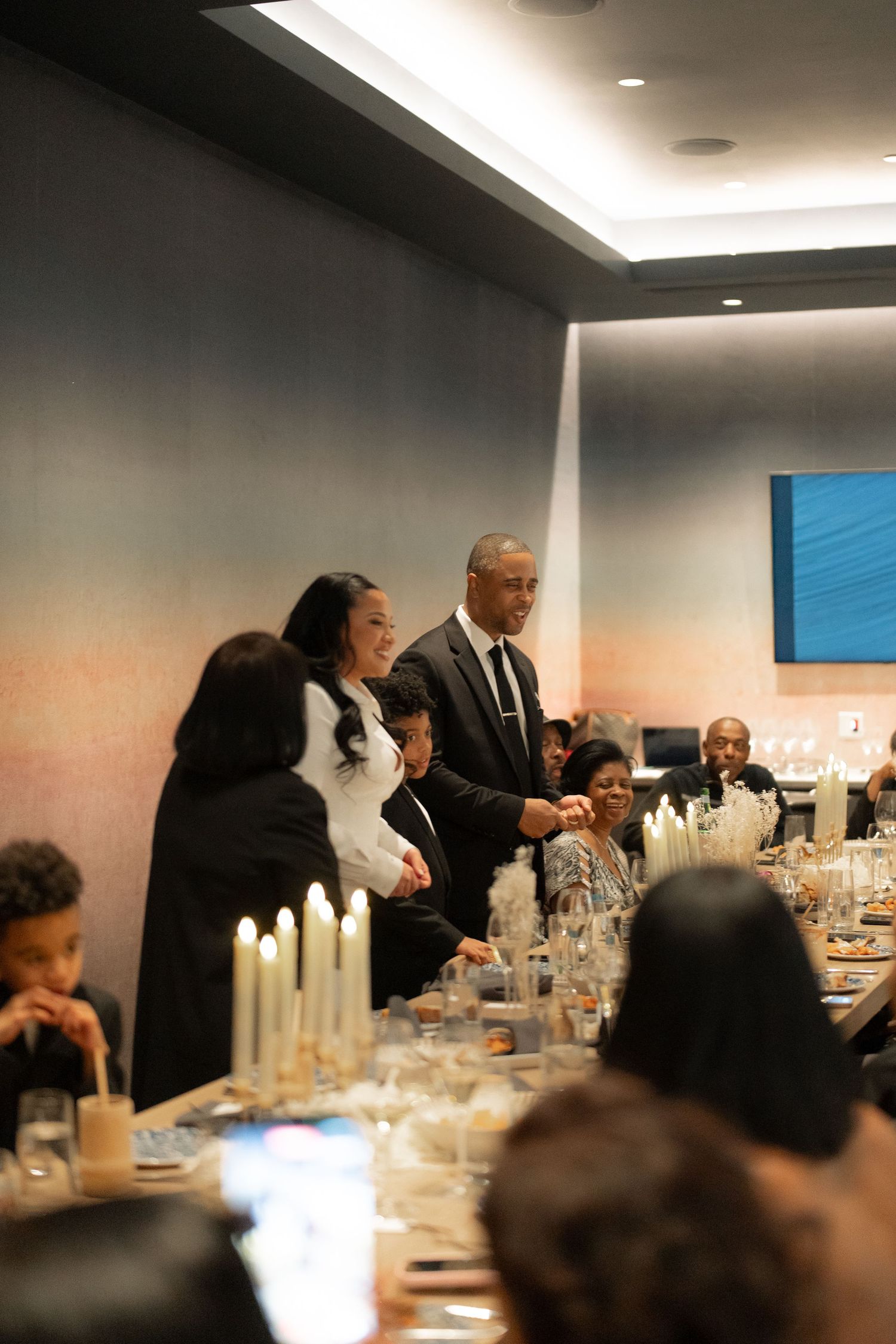 Guests mingling at an elegant dinner party with candlelit table settings.