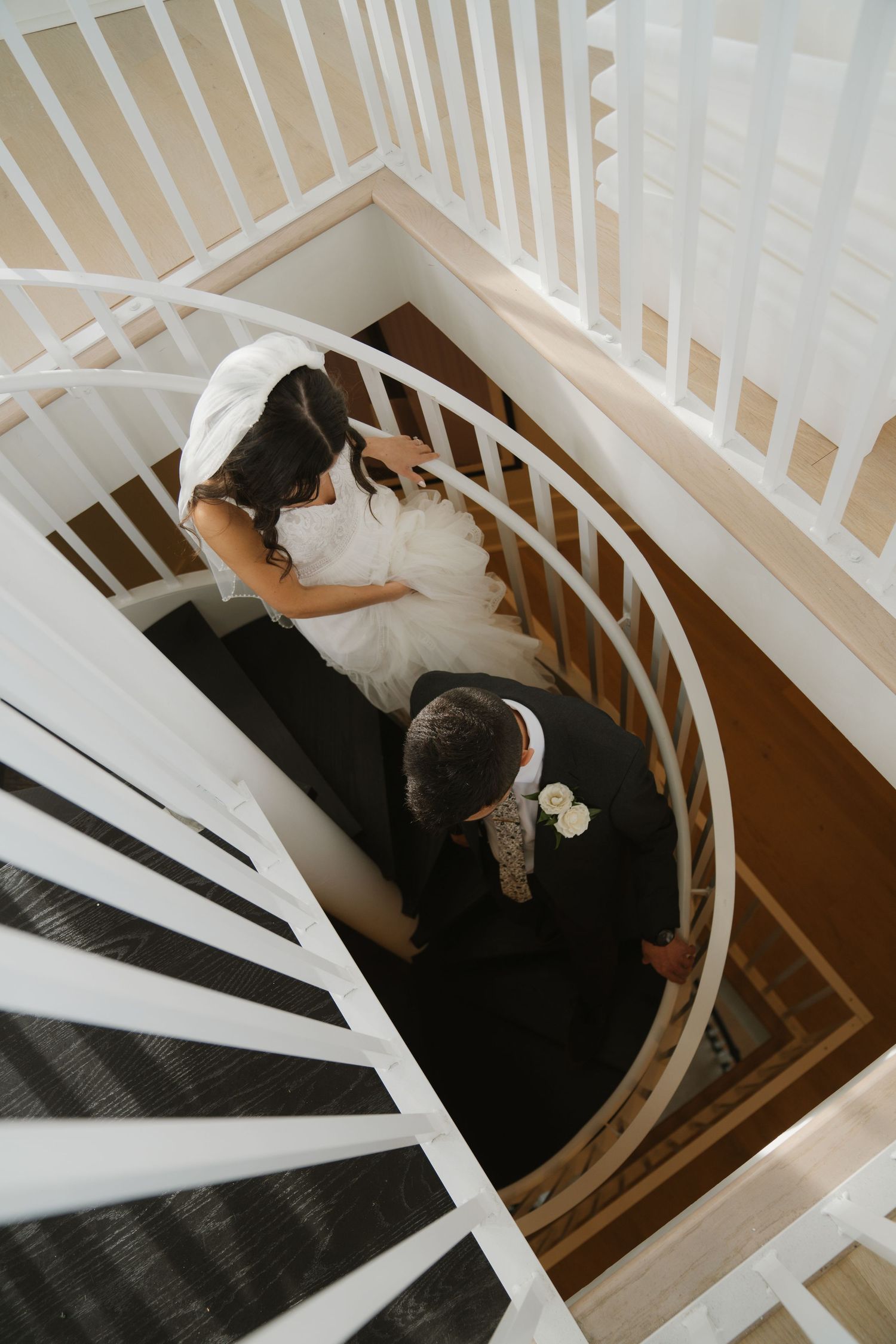 Looking down a white spiral staircase as someone in dark clothing descends the steps.