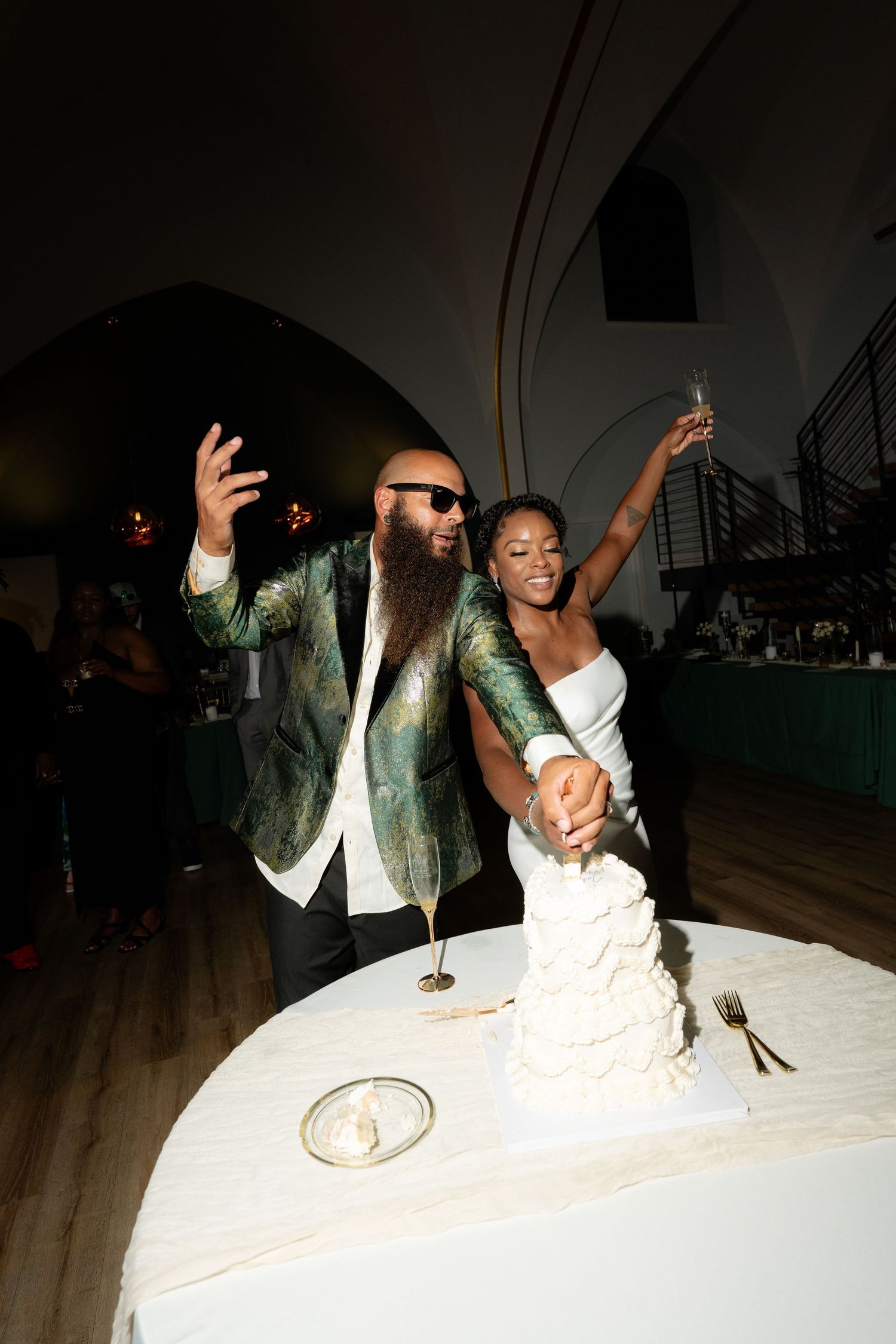 Newlyweds celebrate with enthusiasm while cutting their wedding cake.