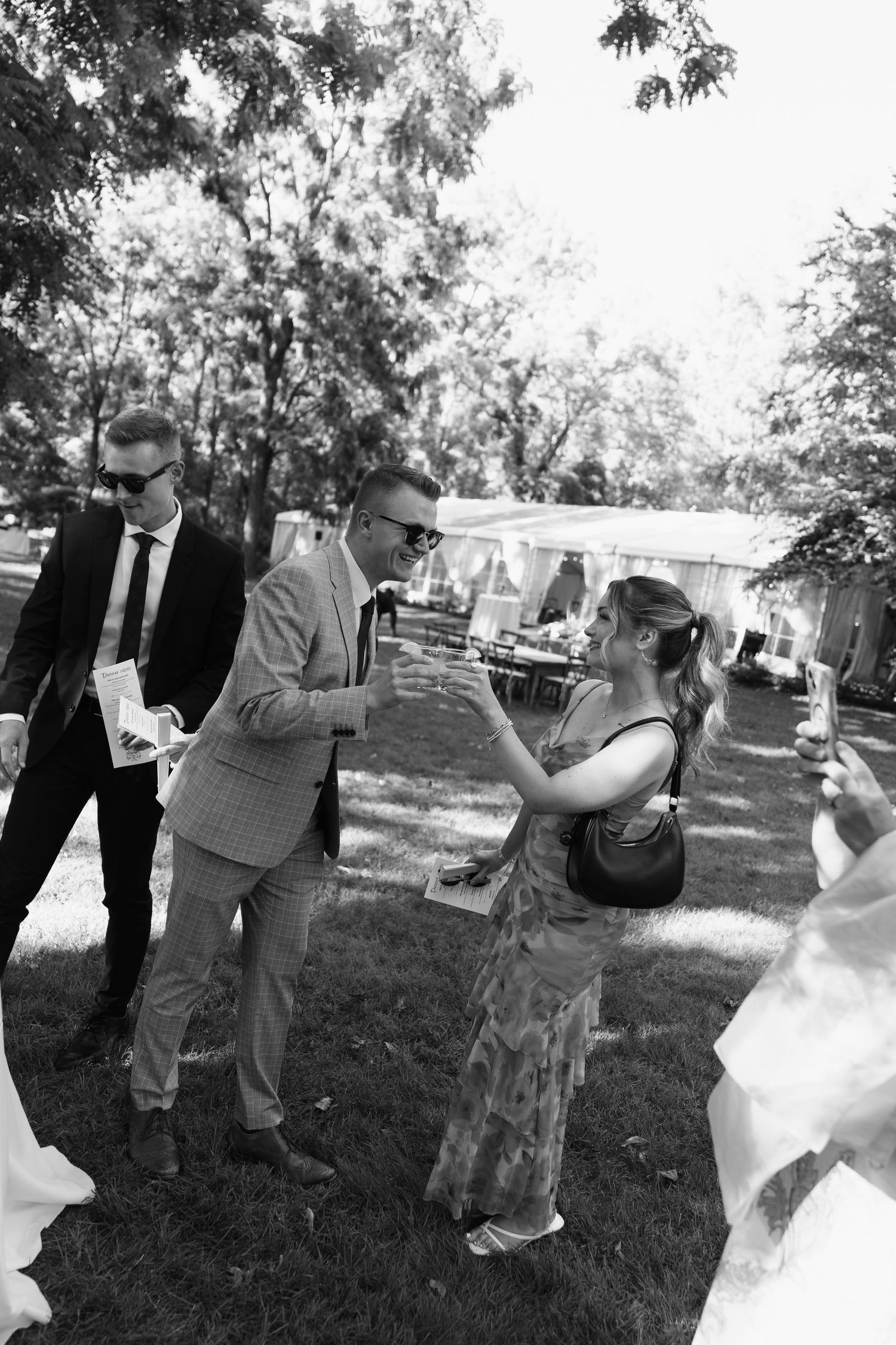 Wedding party members take photos outdoors during a celebration.