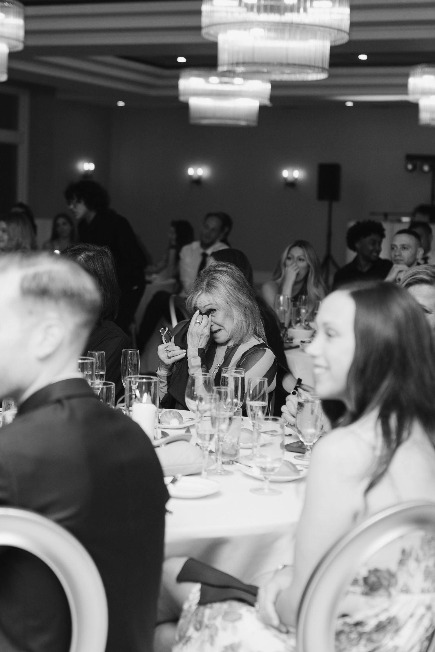 Black and white photograph of guests seated at elegant dining tables during a formal event.