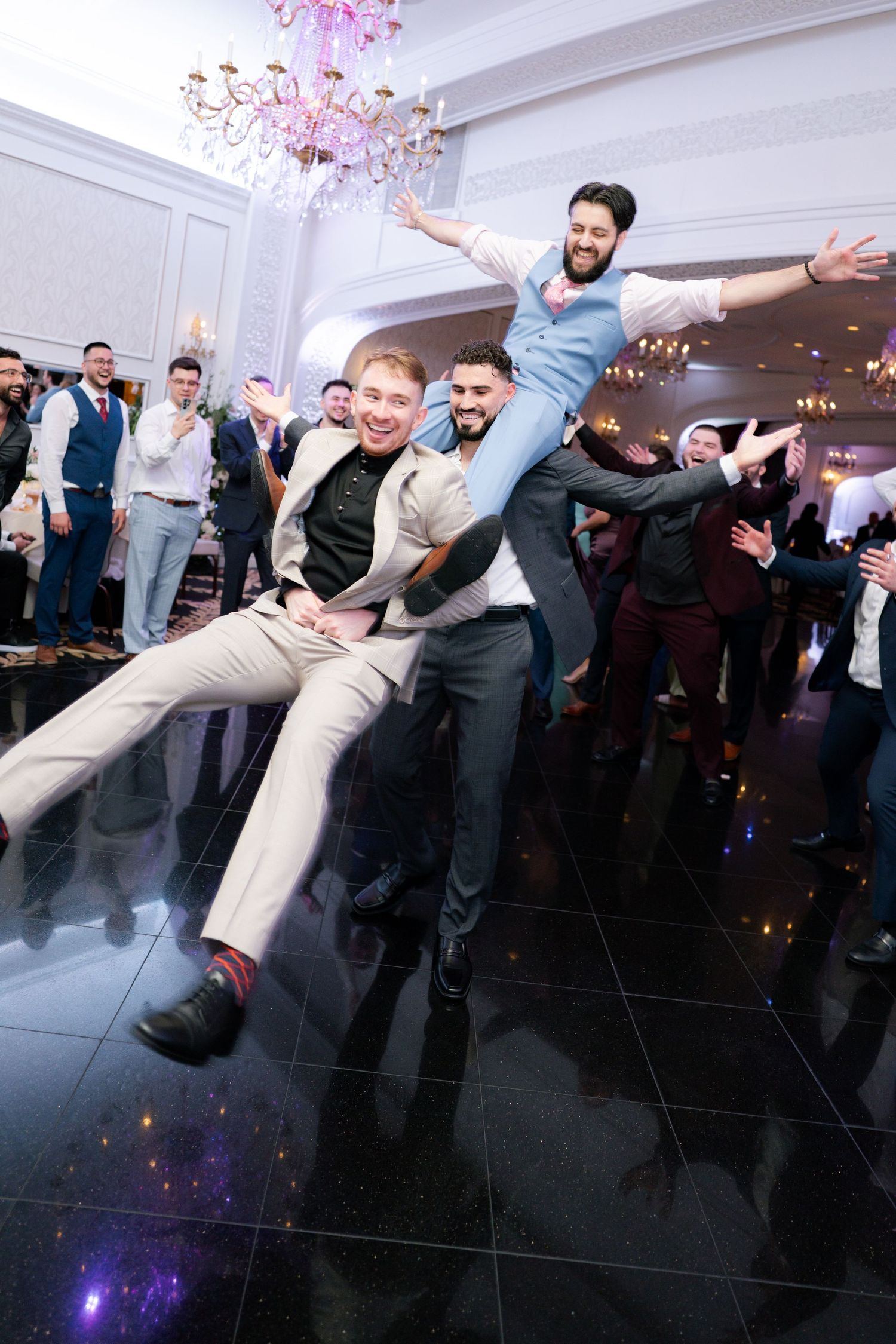 Energetic dance floor moment with guests lifting and celebrating during a wedding reception.