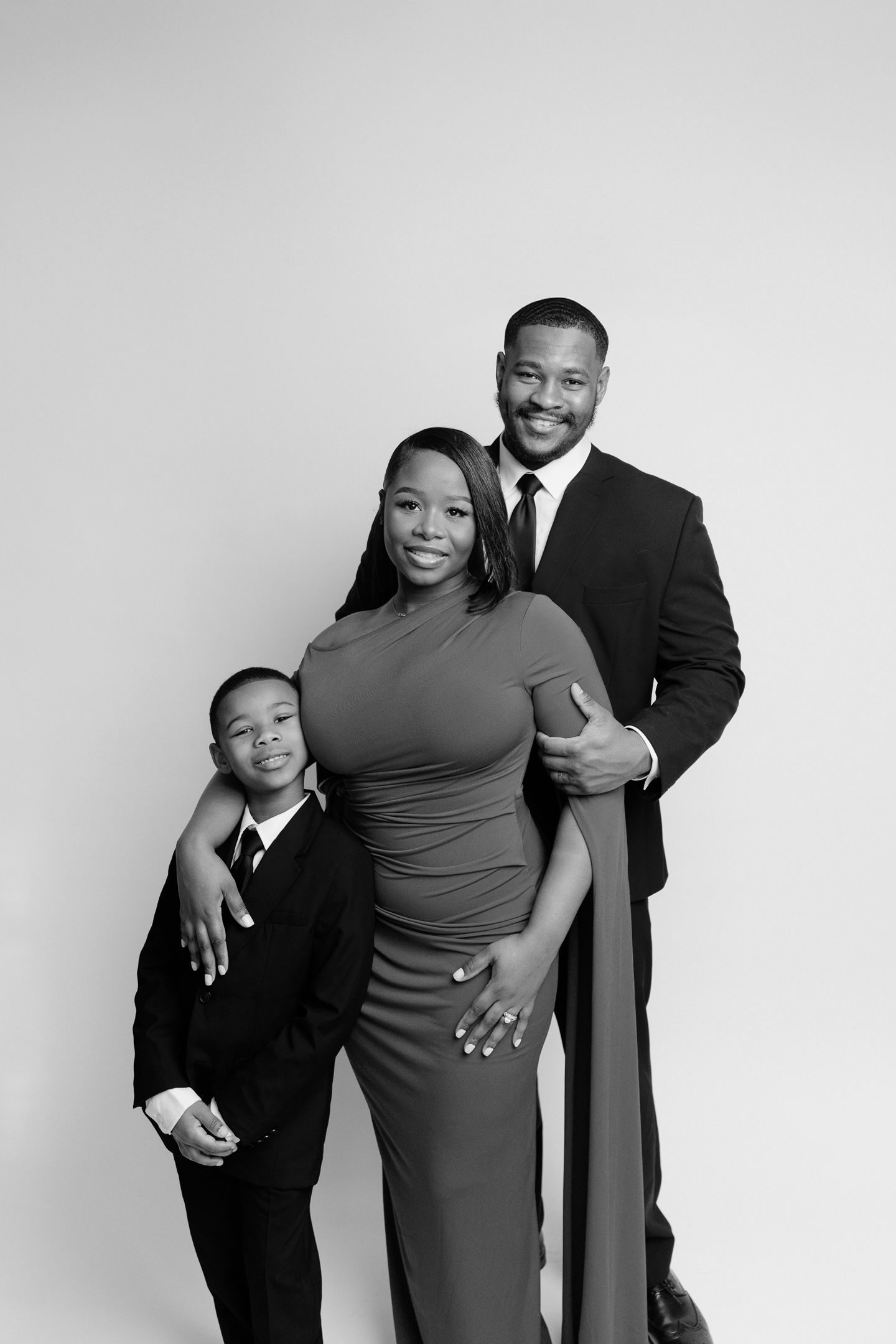 Black and white studio portrait of three people in formal wear.