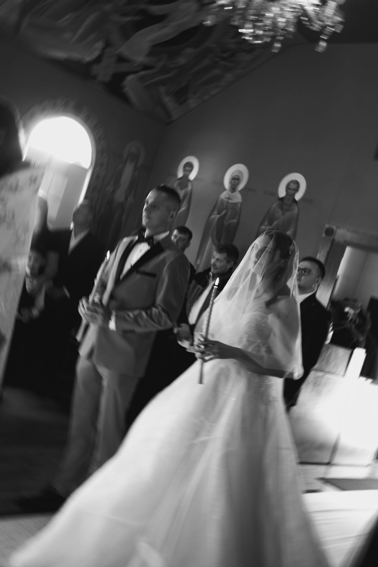 Black and white photo of a bride and groom exchanging vows in an ornate church during their wedding ceremony.