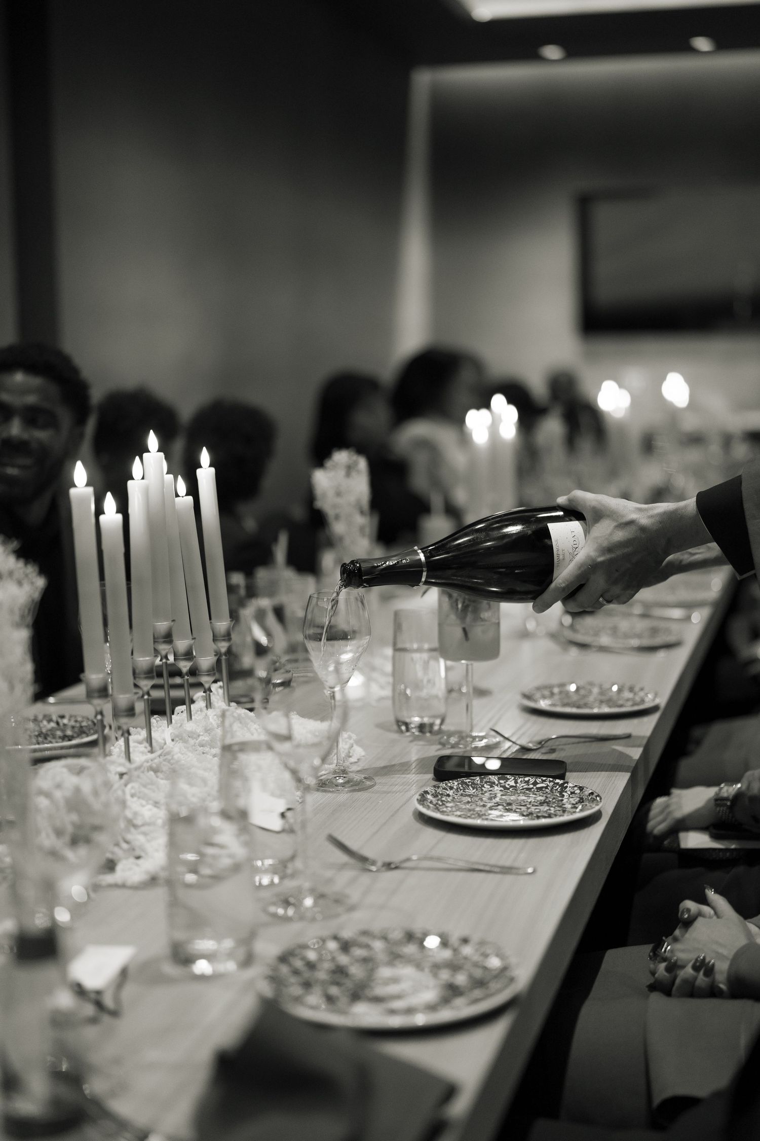 A formal dinner table setting with glassware and decorative elements in soft focus black and white.