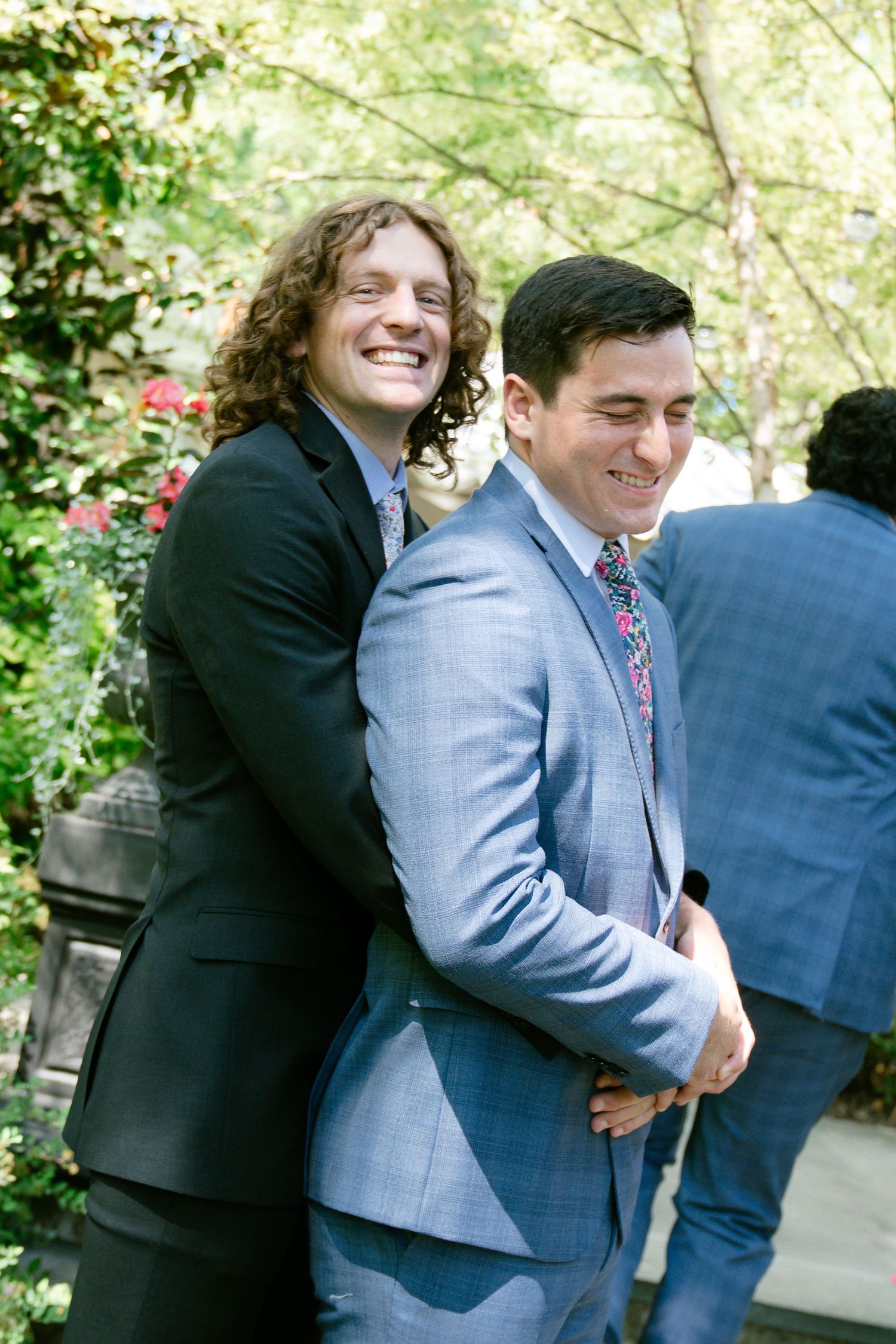 Candid sequence showing groomsmen in suits hugging and laughing together outdoors.
