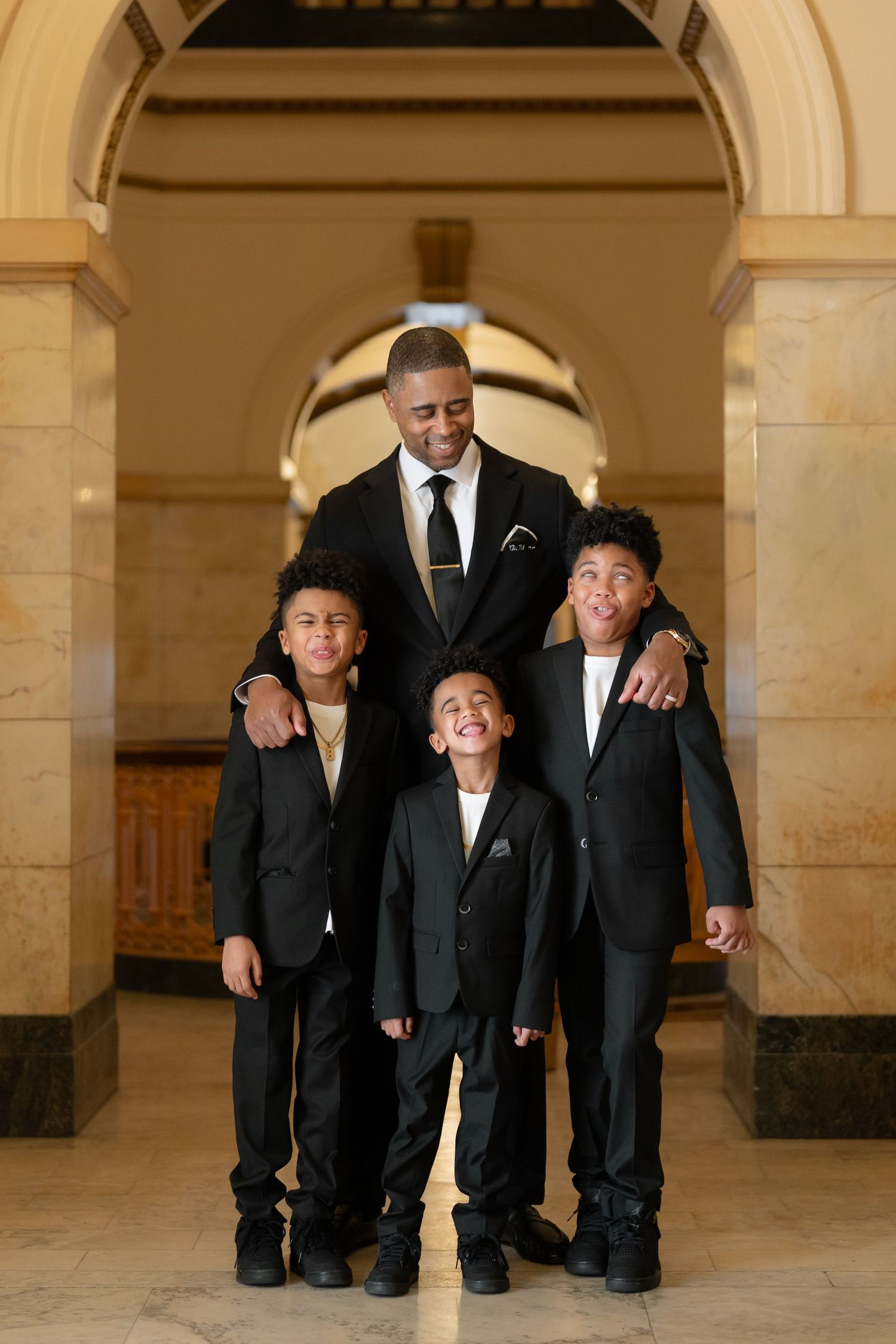 A series of candid photos showing a group in formal black suits posing together in an elegant arched hallway.