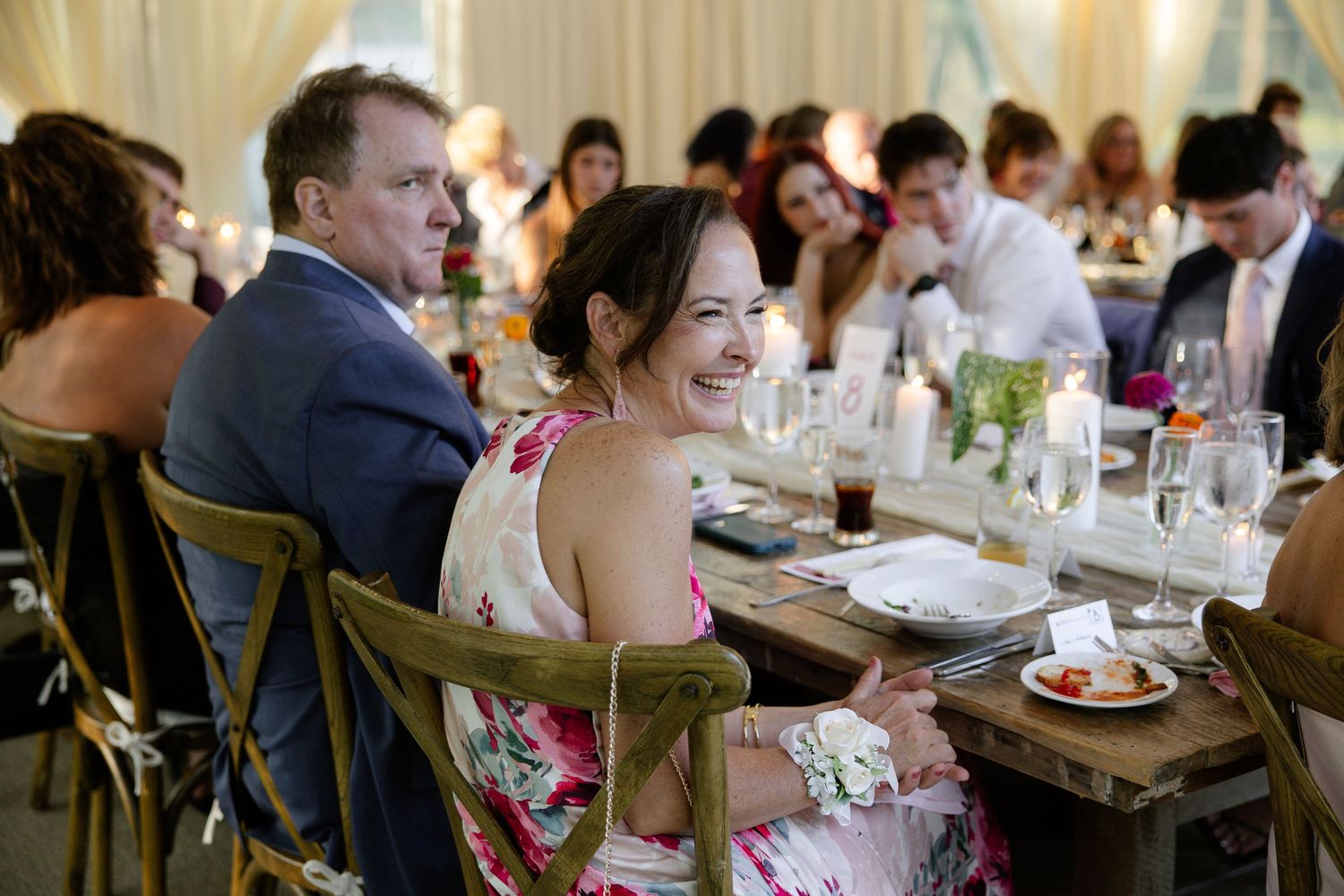 Wedding reception guests seated at decorated tables enjoying their meals.