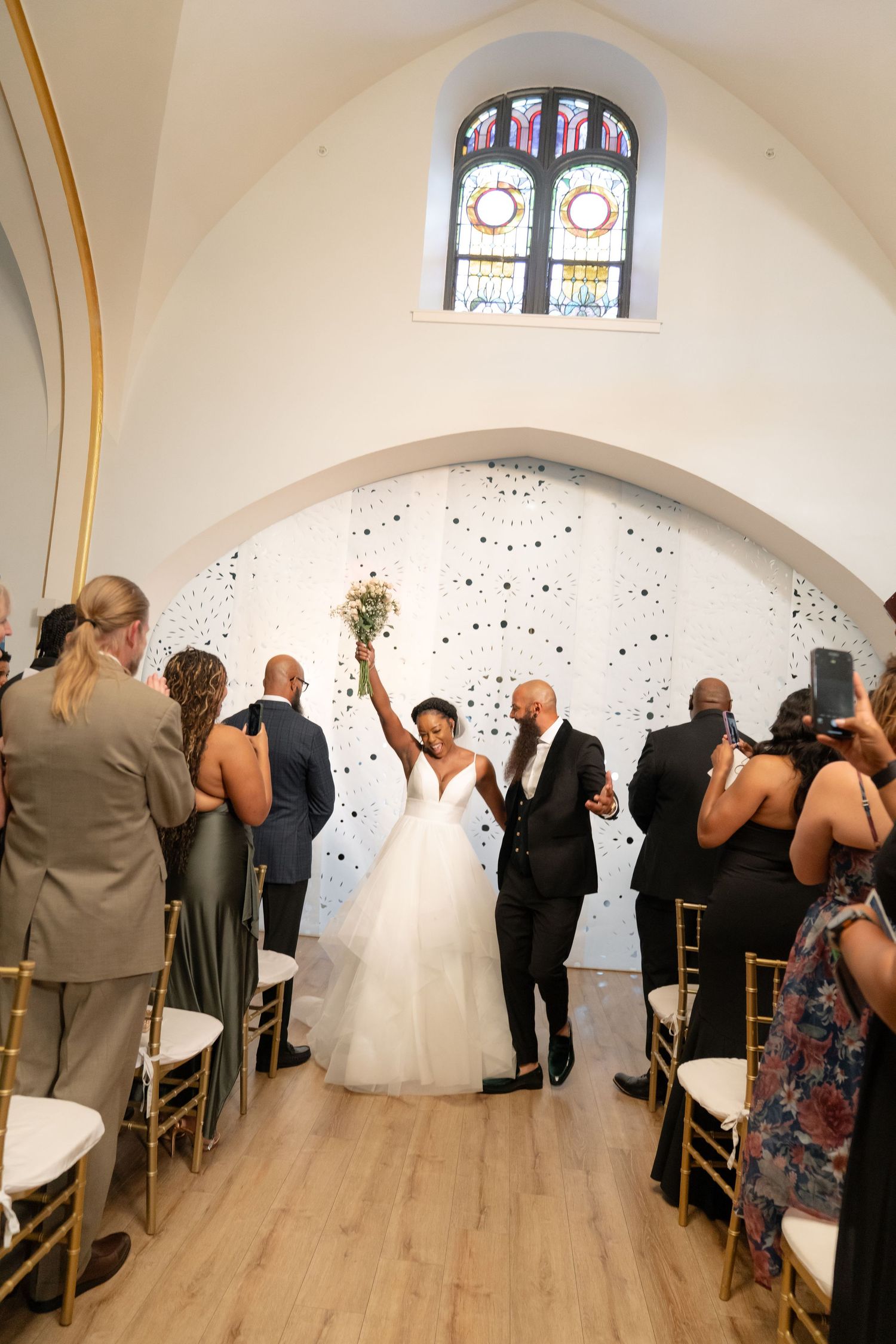 Wedding ceremony setup in a chapel-like space with stained glass windows and modern decor.