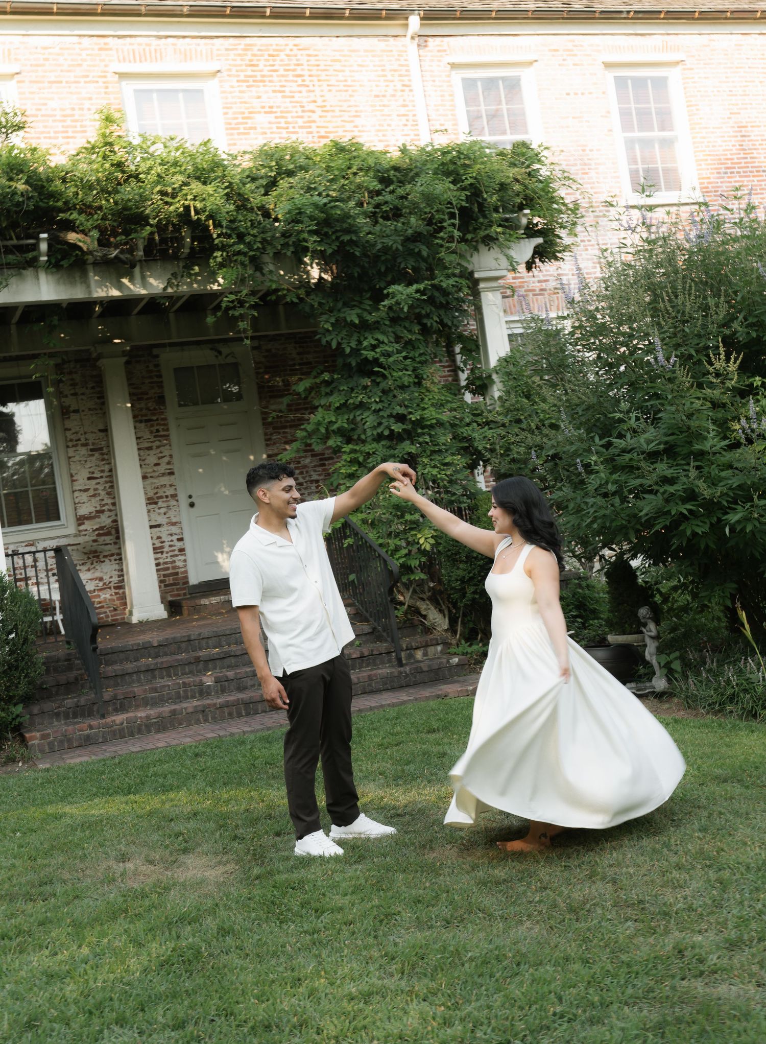 Couple dances playfully on grass during outdoor photo session.