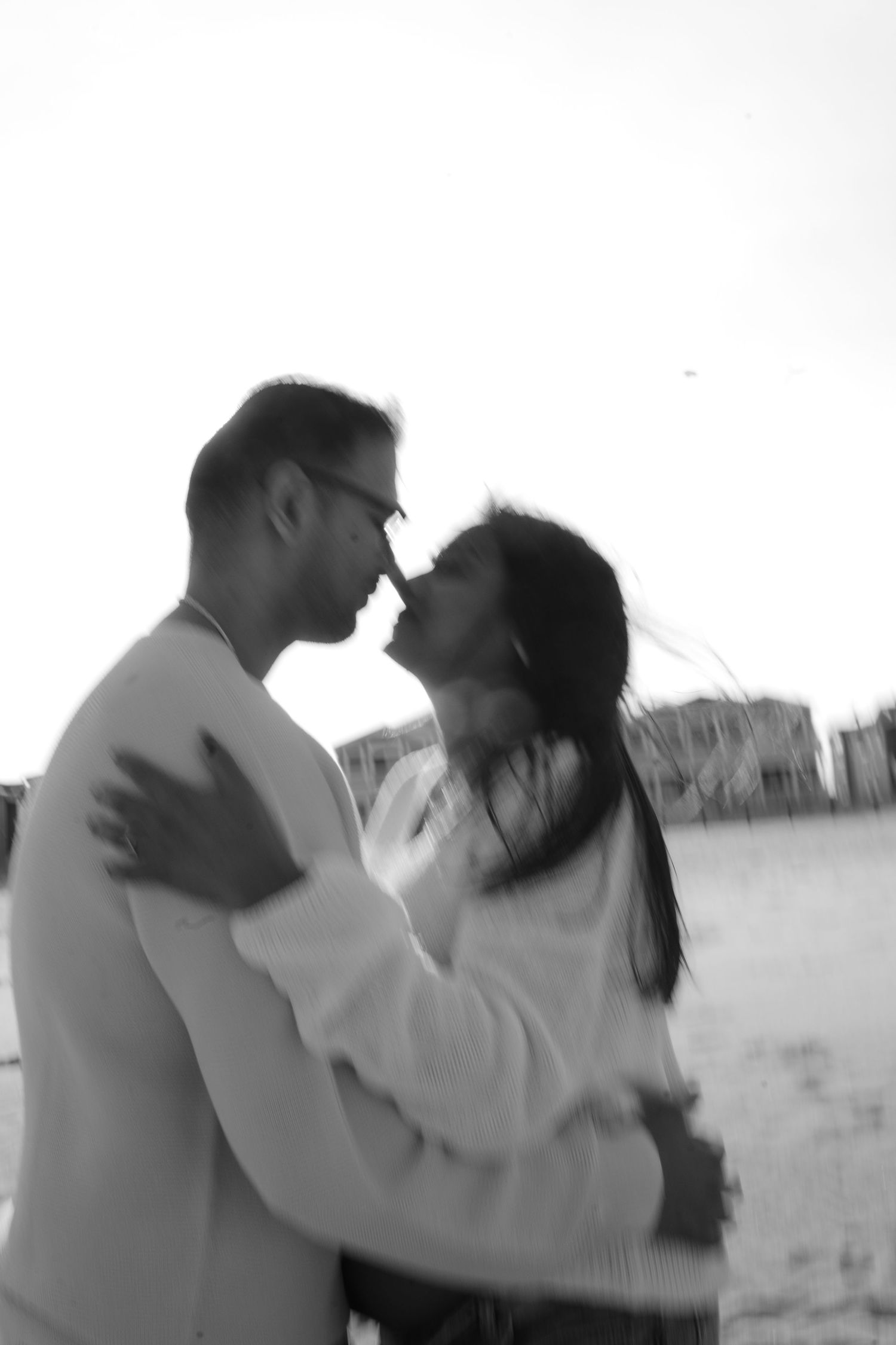 Black and white romantic beach scene with couple dancing in soft focus.