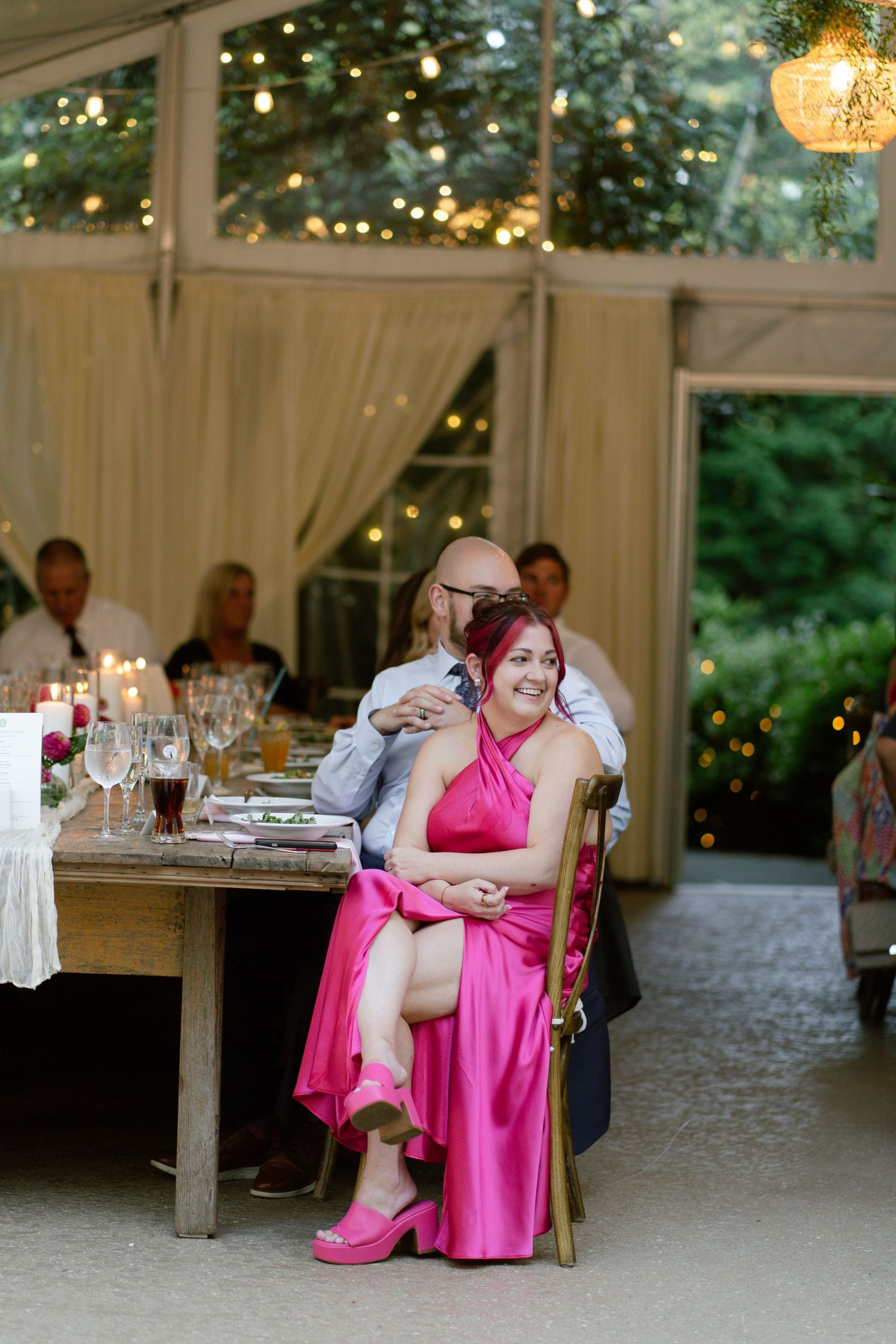 Wedding reception venue with string lights and white drapes creating an elegant indoor-outdoor atmosphere.