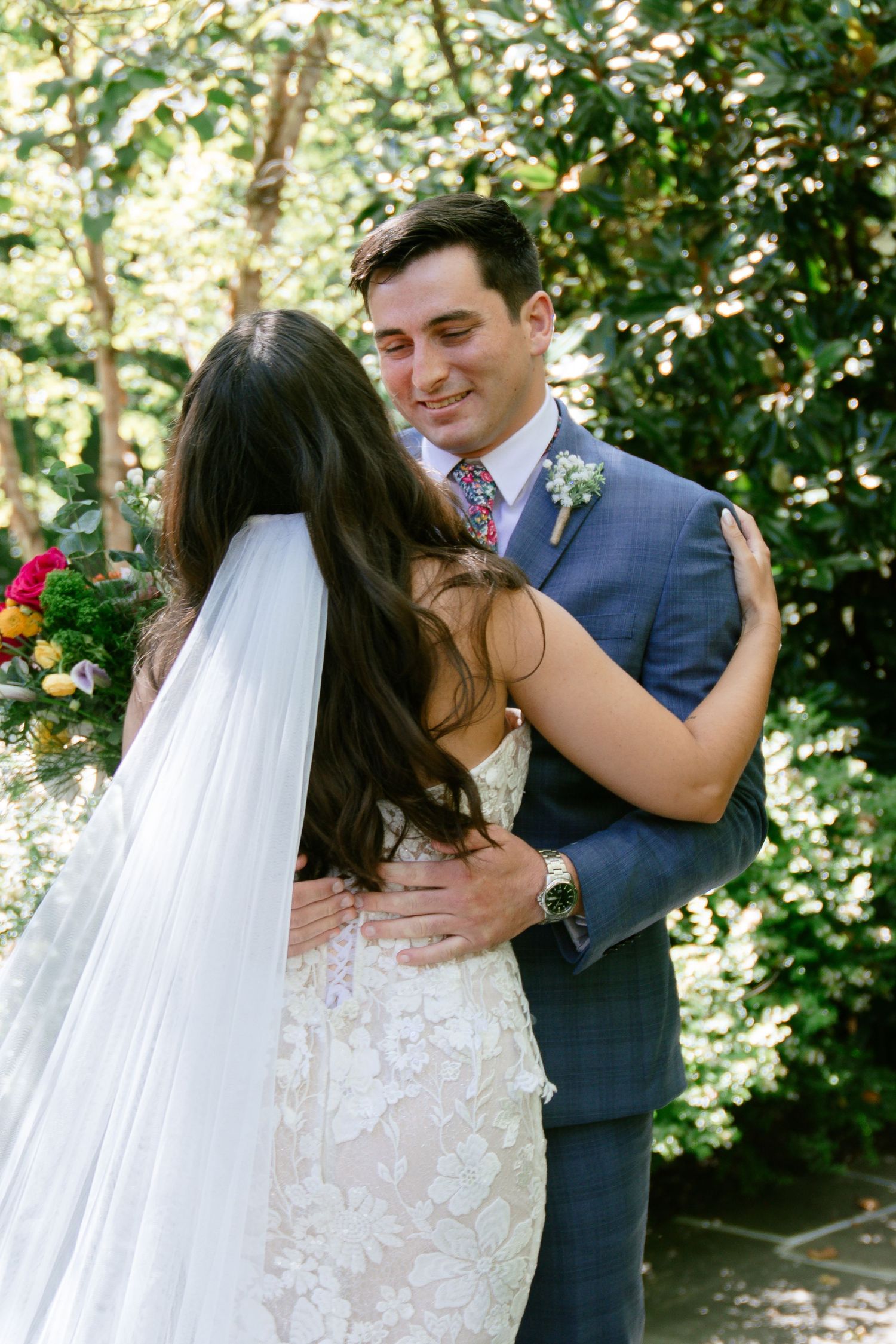 A romantic wedding moment captured in a garden setting with natural sunlight filtering through trees.