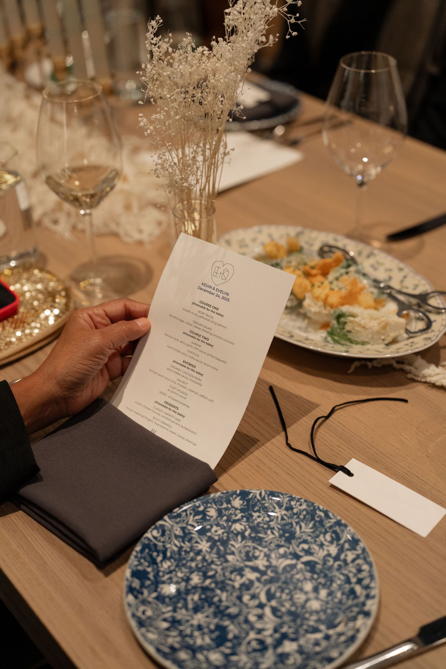 Wedding reception place settings featuring blue and white patterned plates and printed menus.