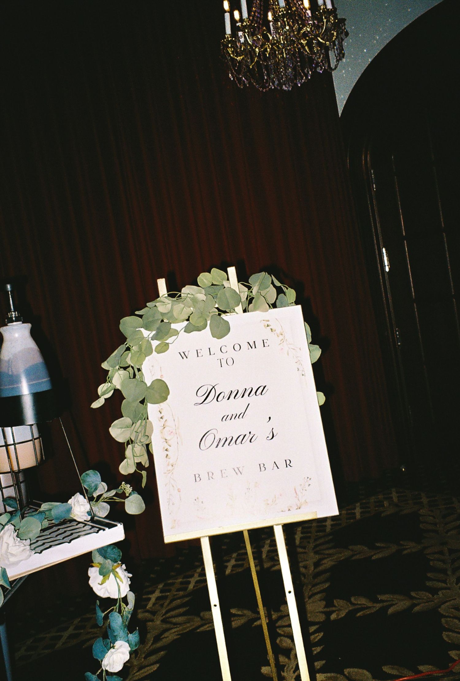 Welcome sign decorated with eucalyptus leaves at an elegant wedding reception.