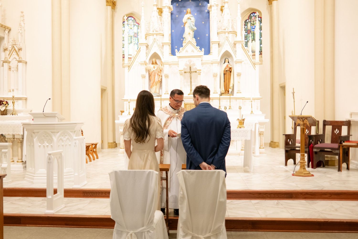 A church sanctuary with white walls, stained glass windows, and elegant altar decorations.