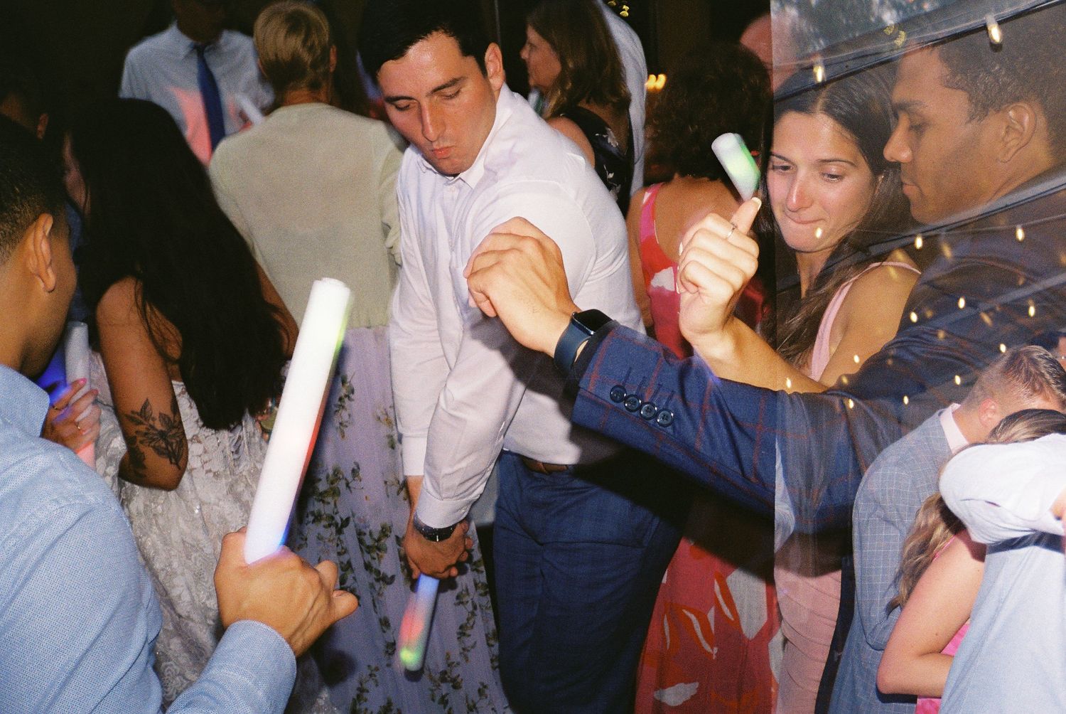 Wedding guests mingling and dancing during evening reception celebration.