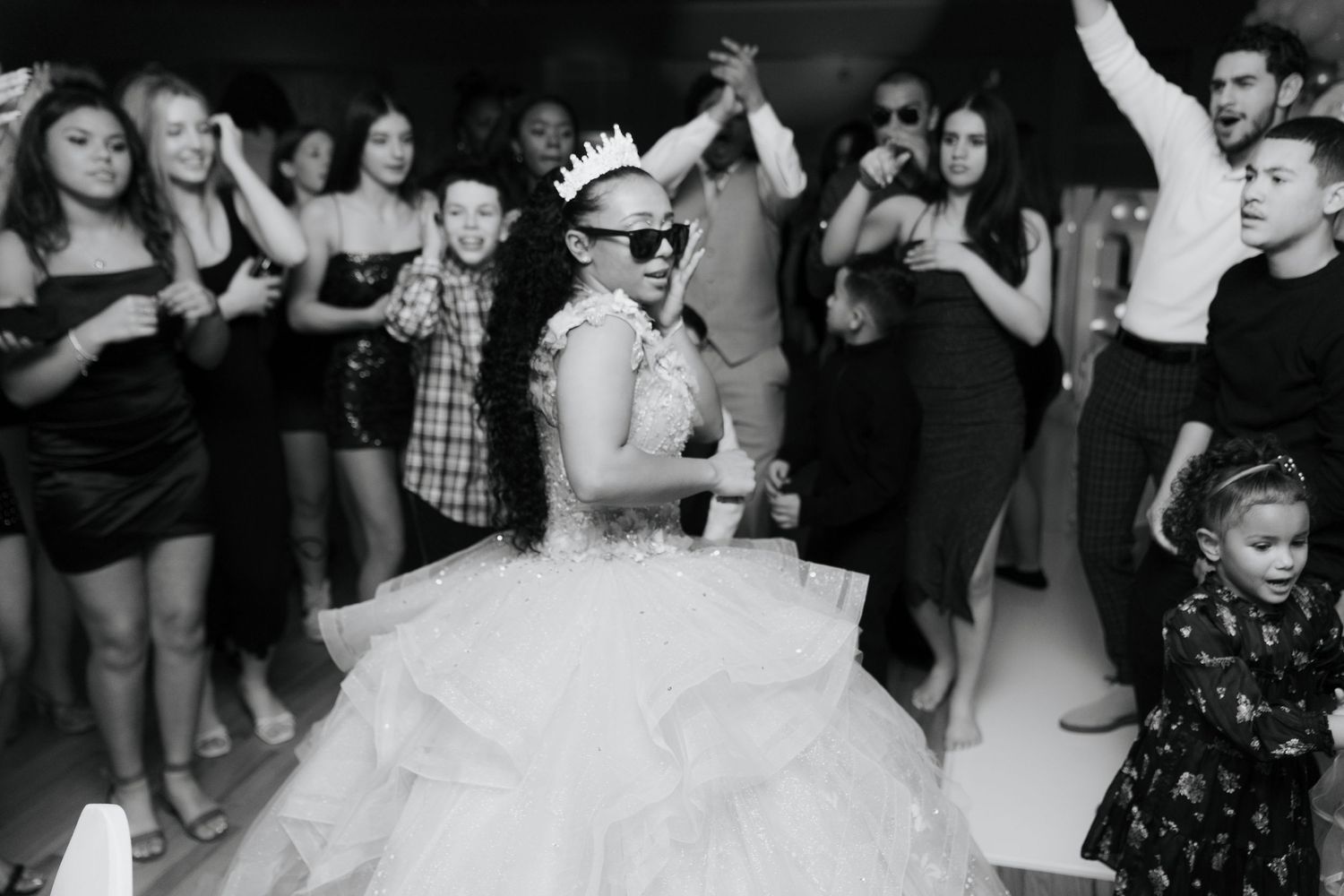 Wedding celebration on a dance floor with guests dancing in black and white.