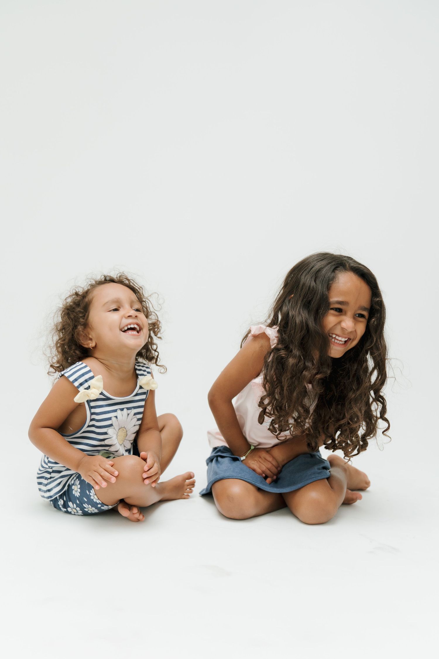 Playful children in striped clothing laughing on white background.