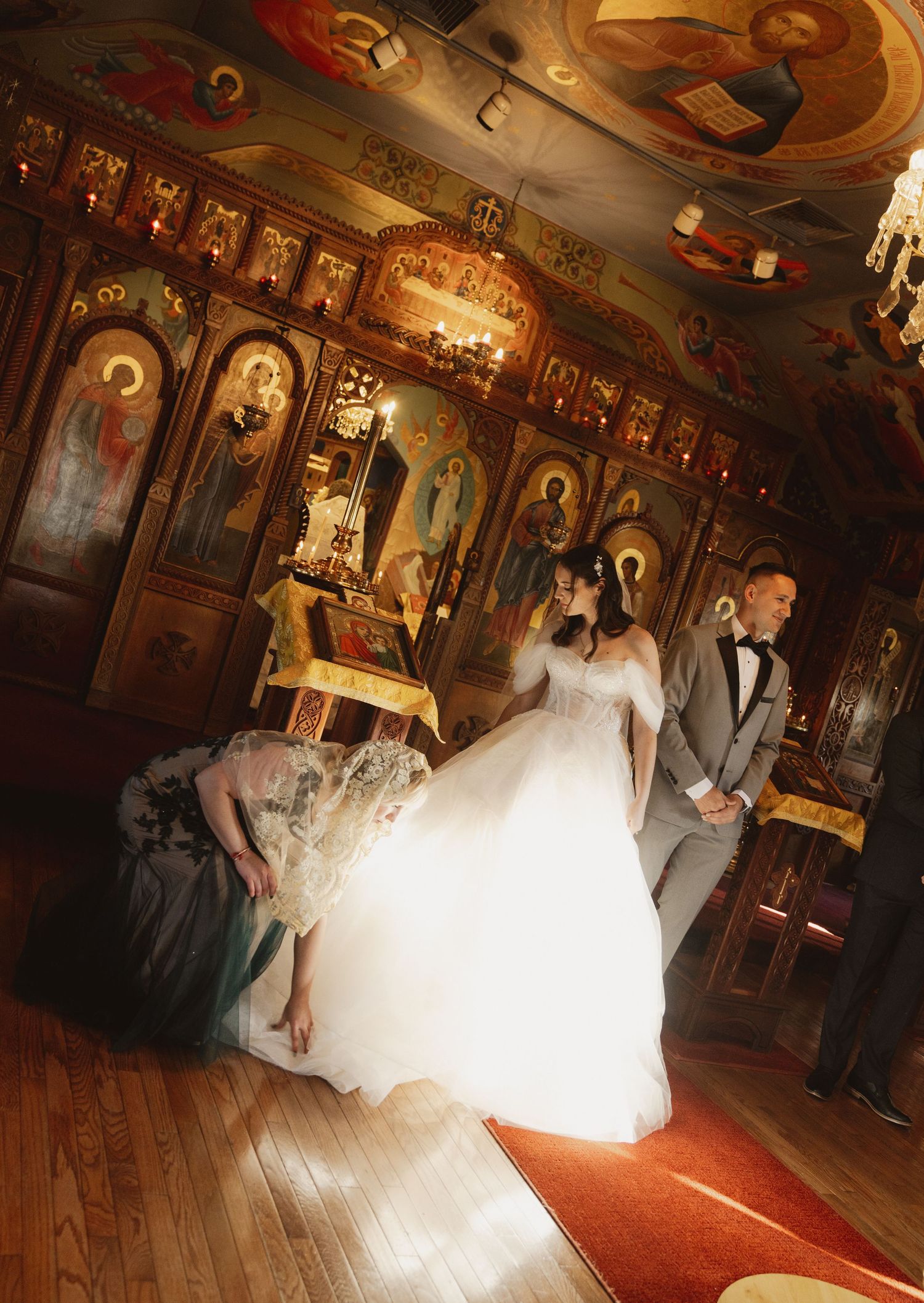 Wedding ceremony taking place in an ornate Orthodox church with traditional religious icons and decorative elements.