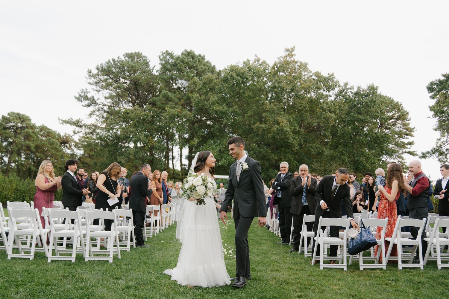 A series of outdoor wedding ceremony photos showing white chairs set up on a green lawn with trees in the background.