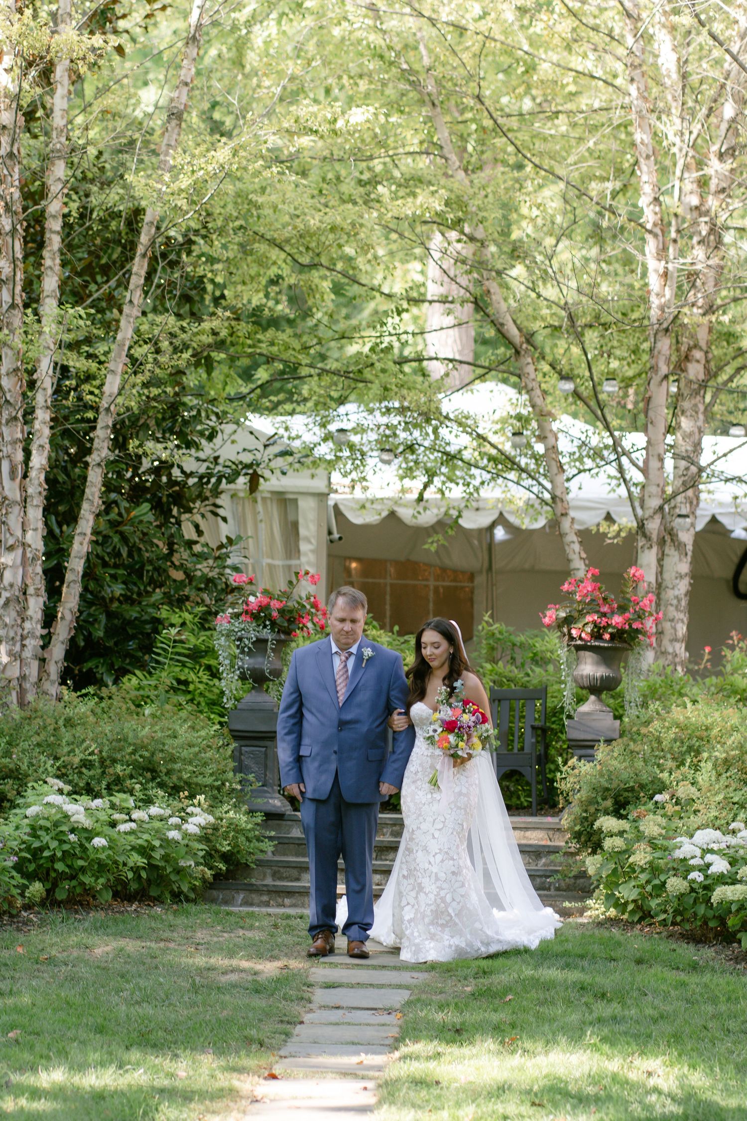 Outdoor garden wedding ceremony with white pergola and birch trees.