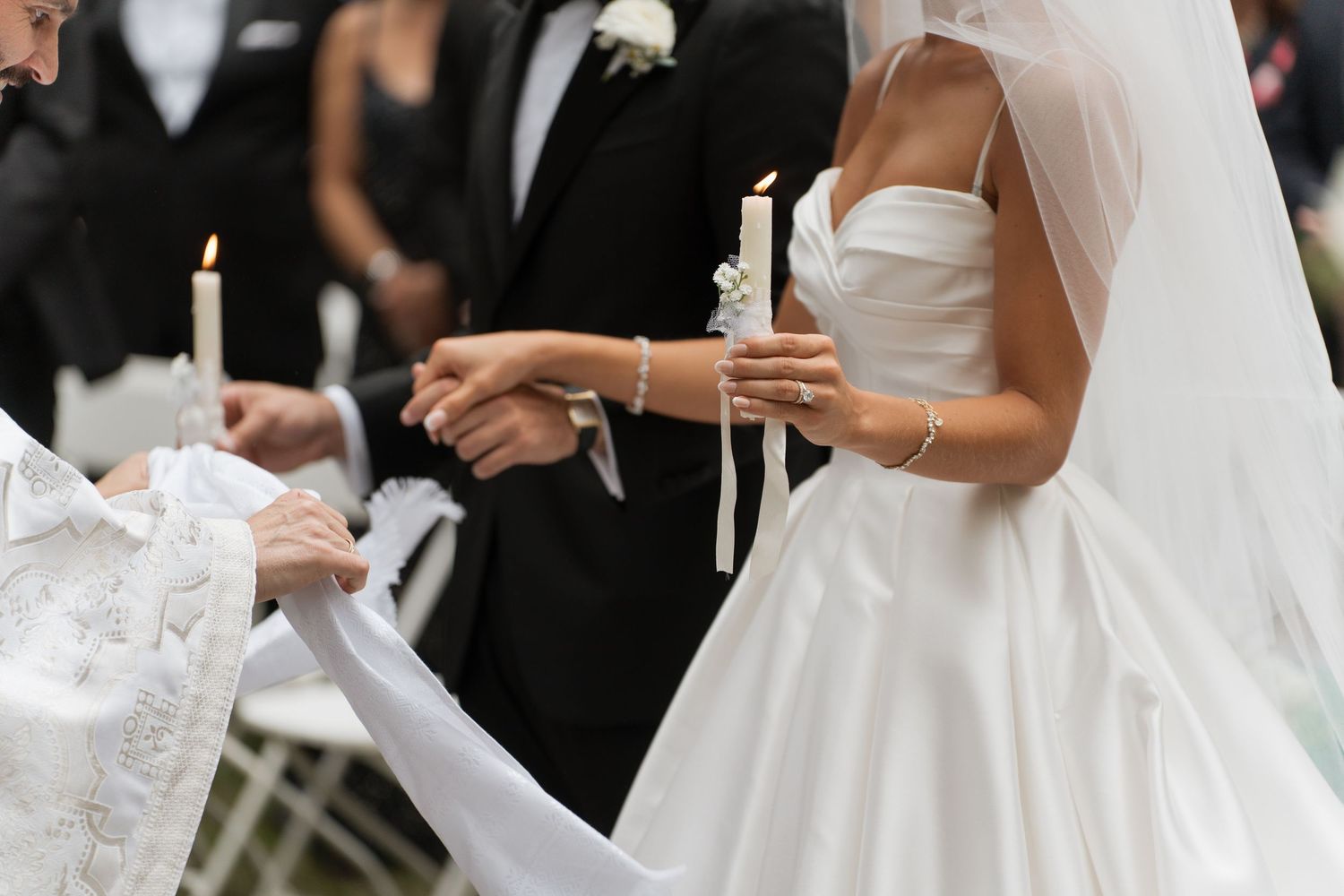 Bride and groom lighting unity candles during outdoor wedding ceremony, bride wearing strapless white ball gown.