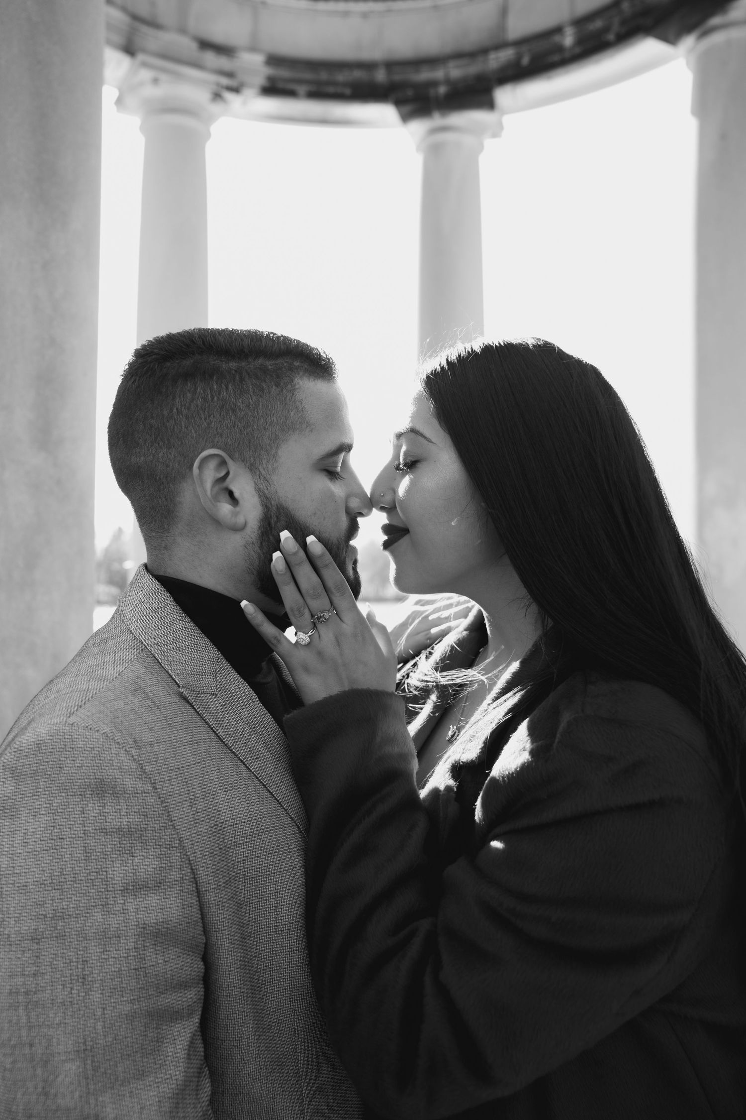 Black and white romantic moment captured under a columned structure.