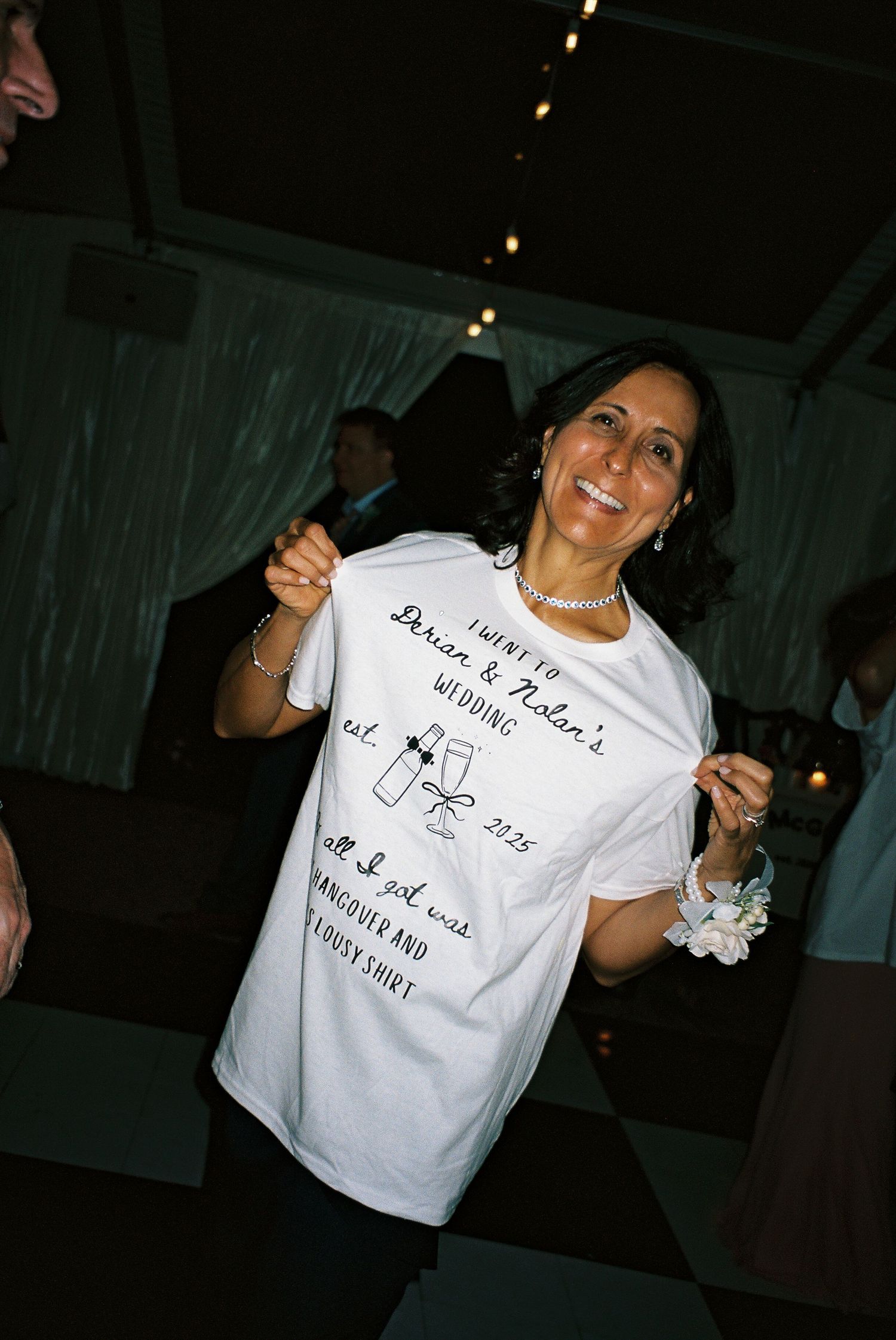 Wedding guest showing off custom celebration t-shirt at reception party.