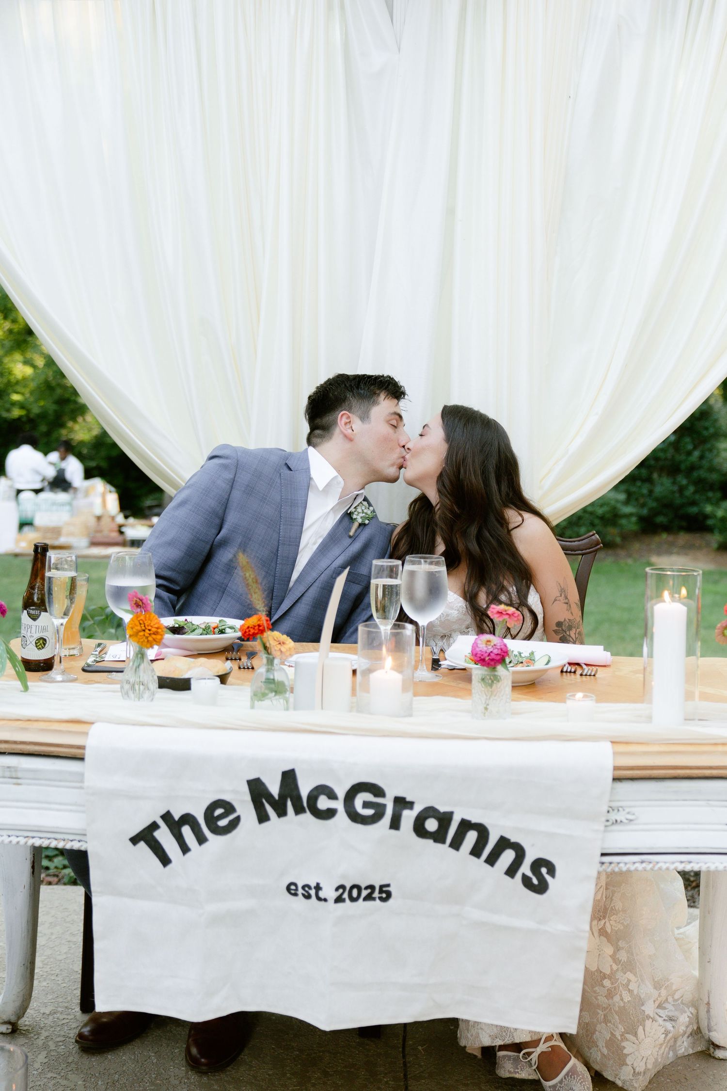 Wedding reception table with personalized banner and romantic moments between the couple.