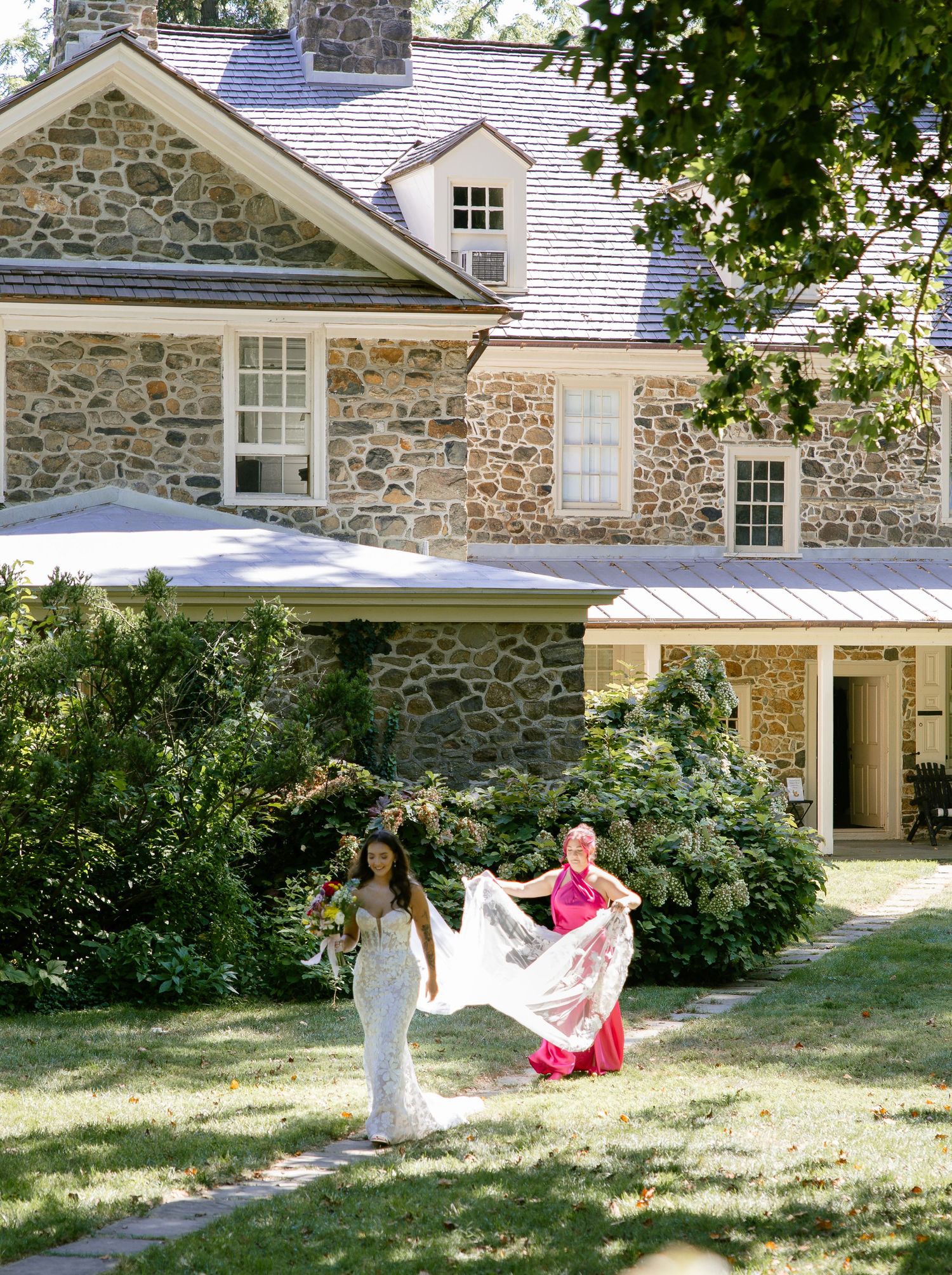 Stone house exterior serves as backdrop for wedding photos on a sunny summer day.