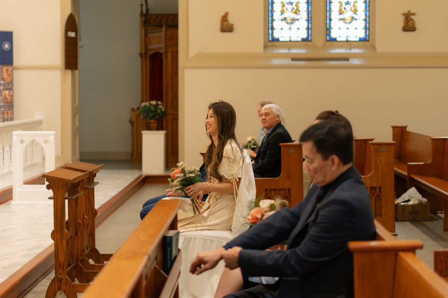 Intimate church wedding ceremony with guests seated in wooden pews.
