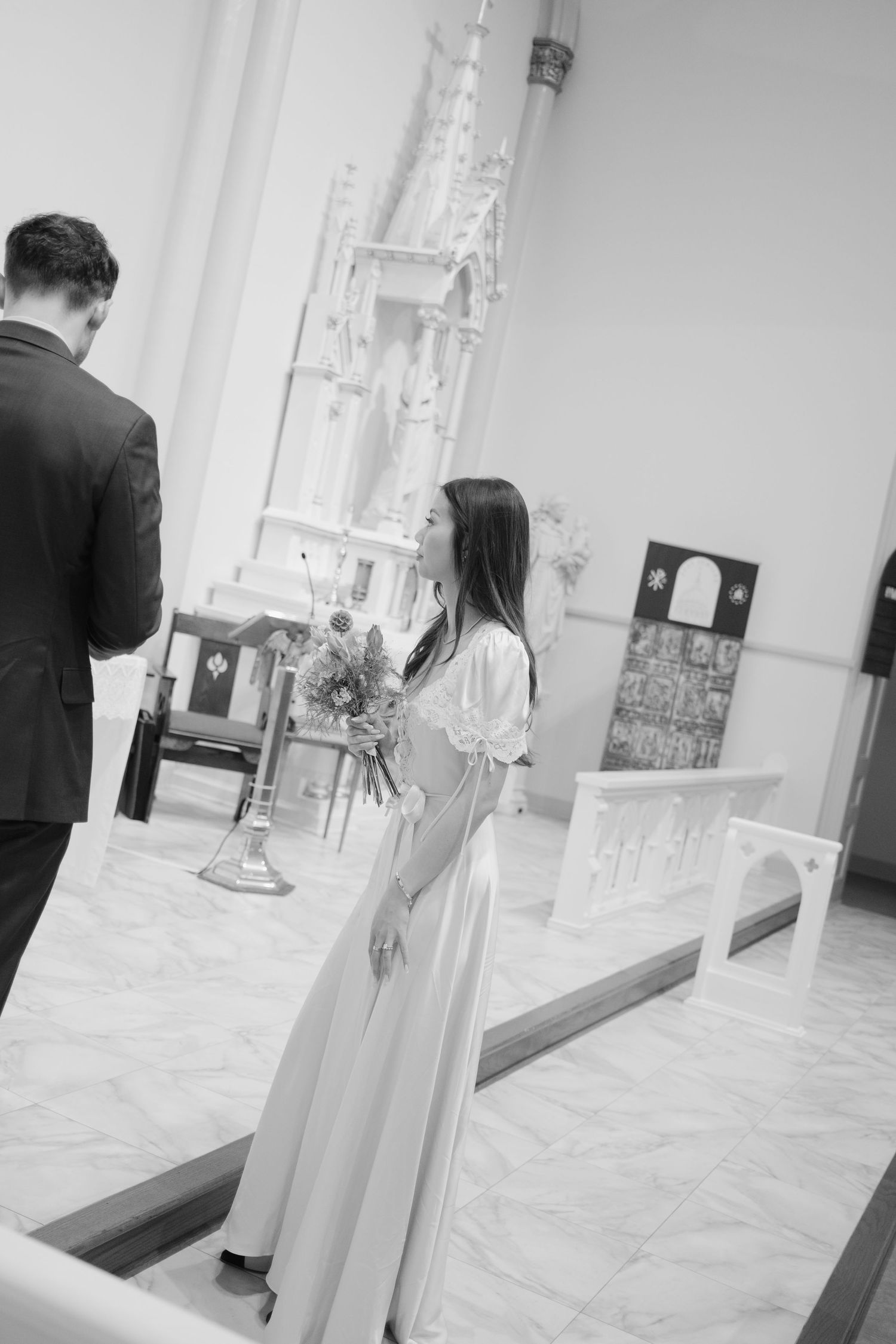 A couple walks through a bright, modern church interior with marble floors.