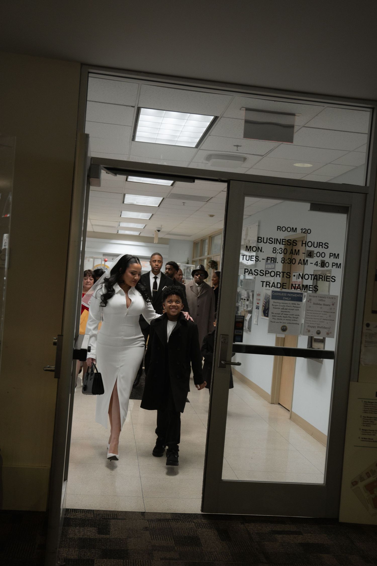 A formal gathering in a hallway with people walking through an institutional doorway.
