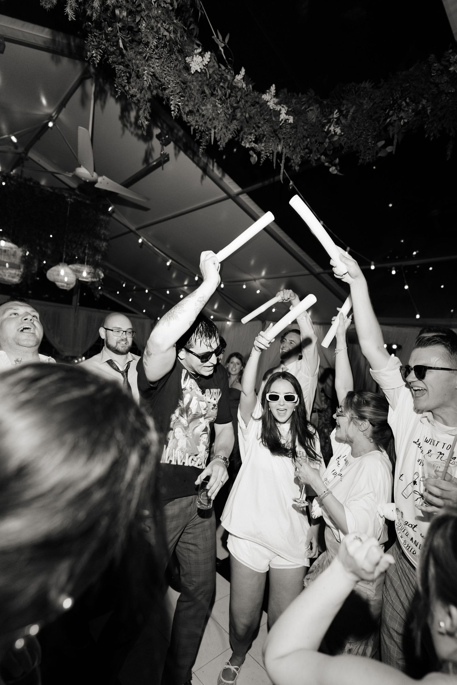 Black and white photo series of people dancing and celebrating at a lively party with hands raised in the air.