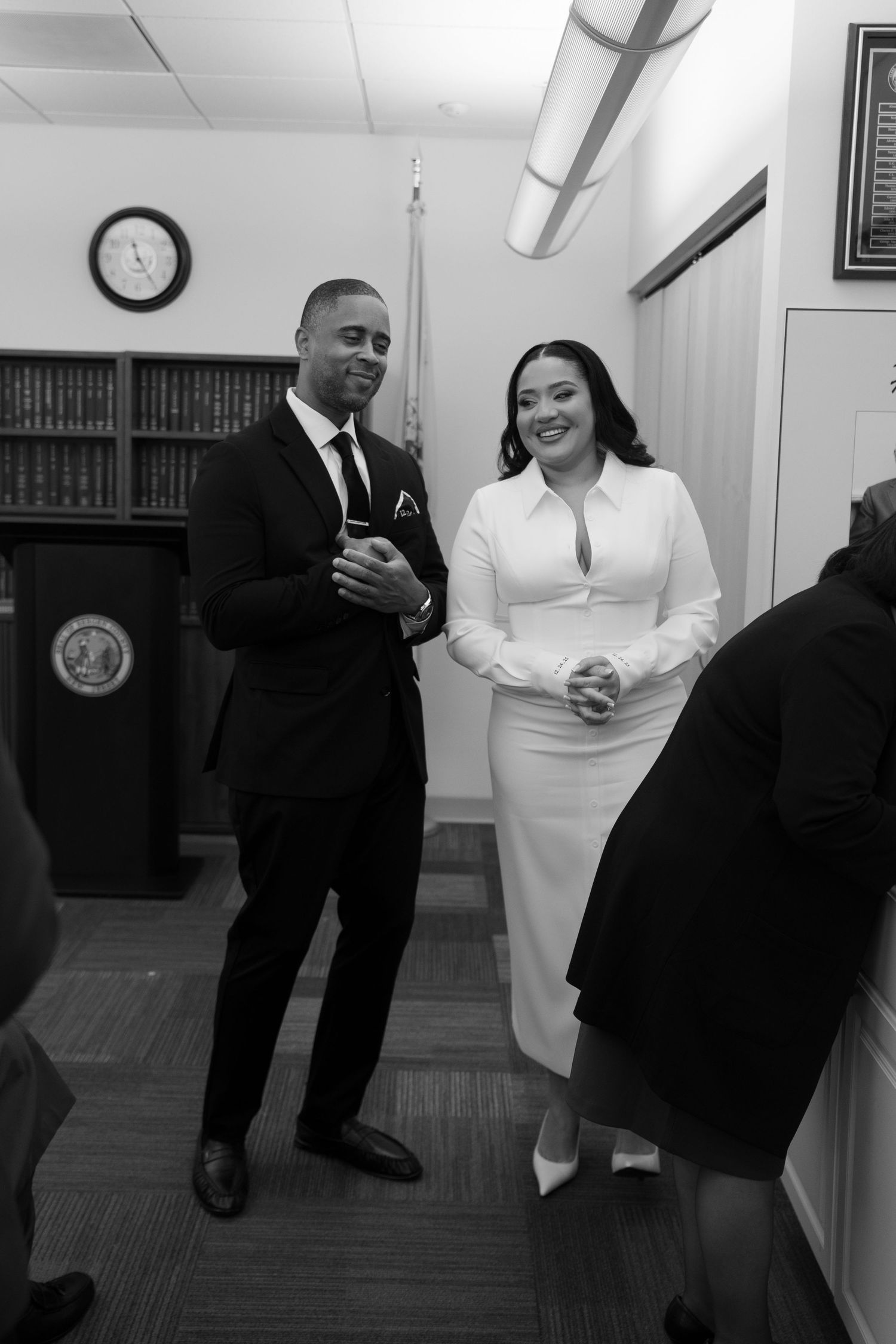 A black and white photo capturing candid moments in an indoor office setting.